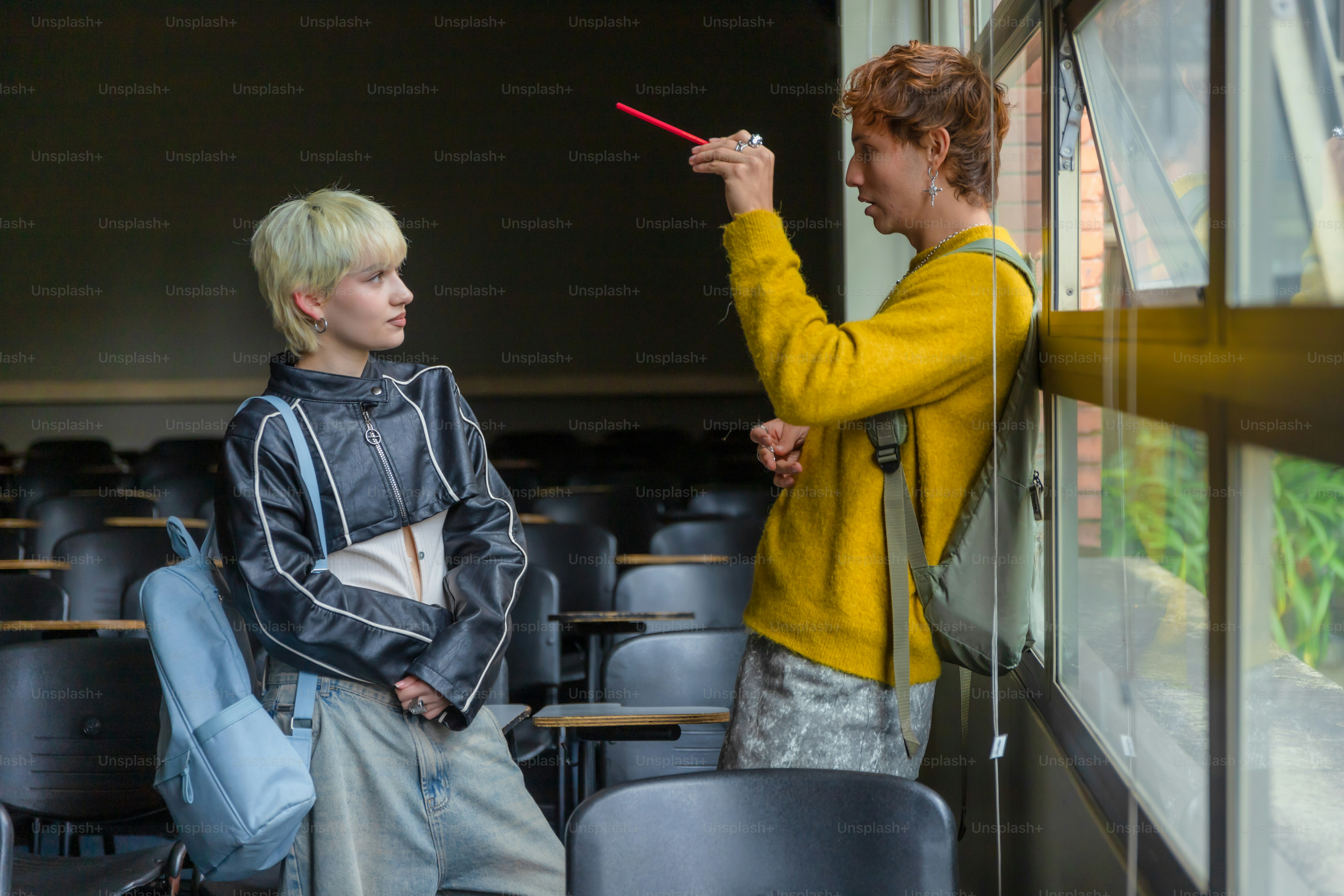 Two students converse in an empty classroom.
