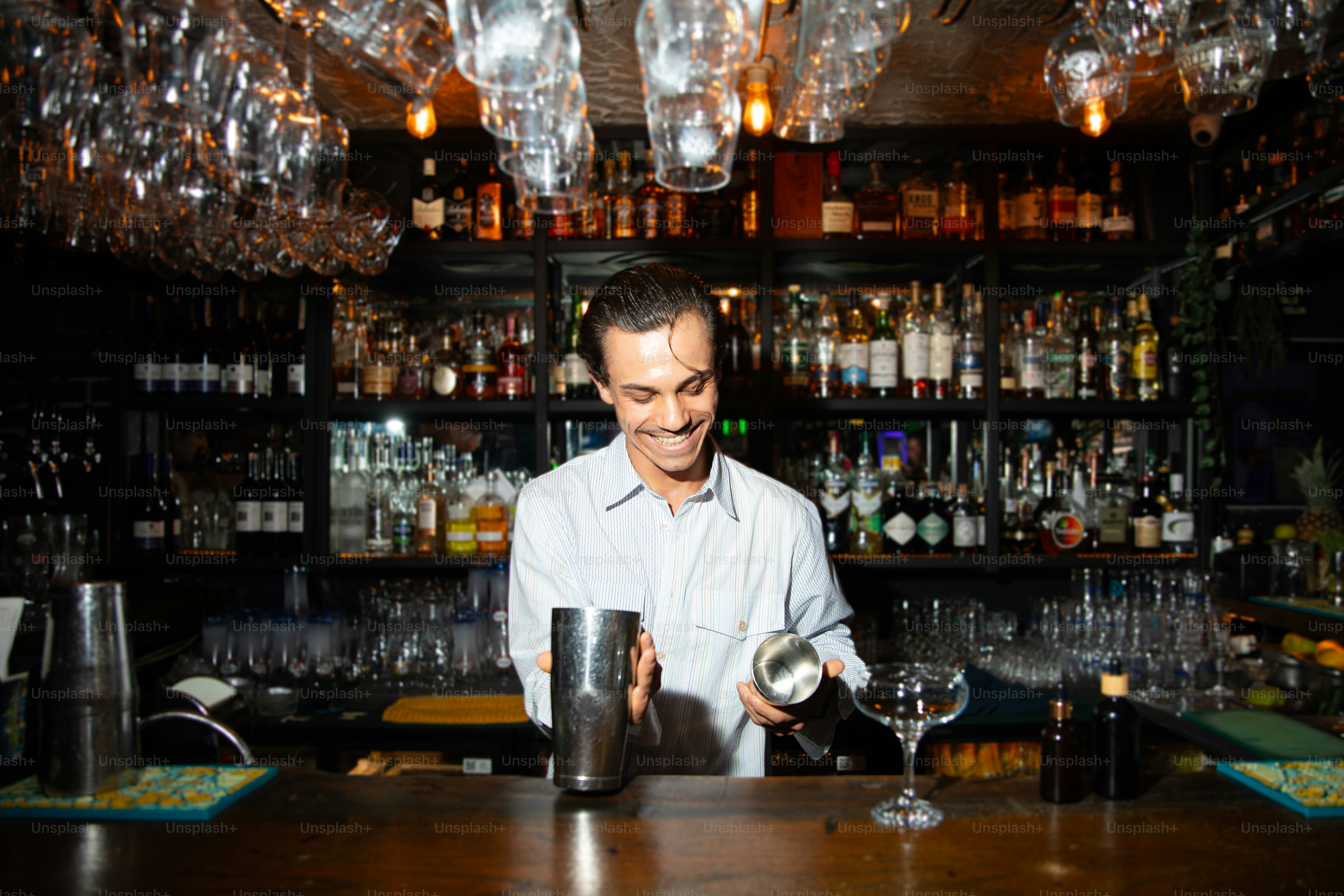 A smiling bartender makes a cocktail.