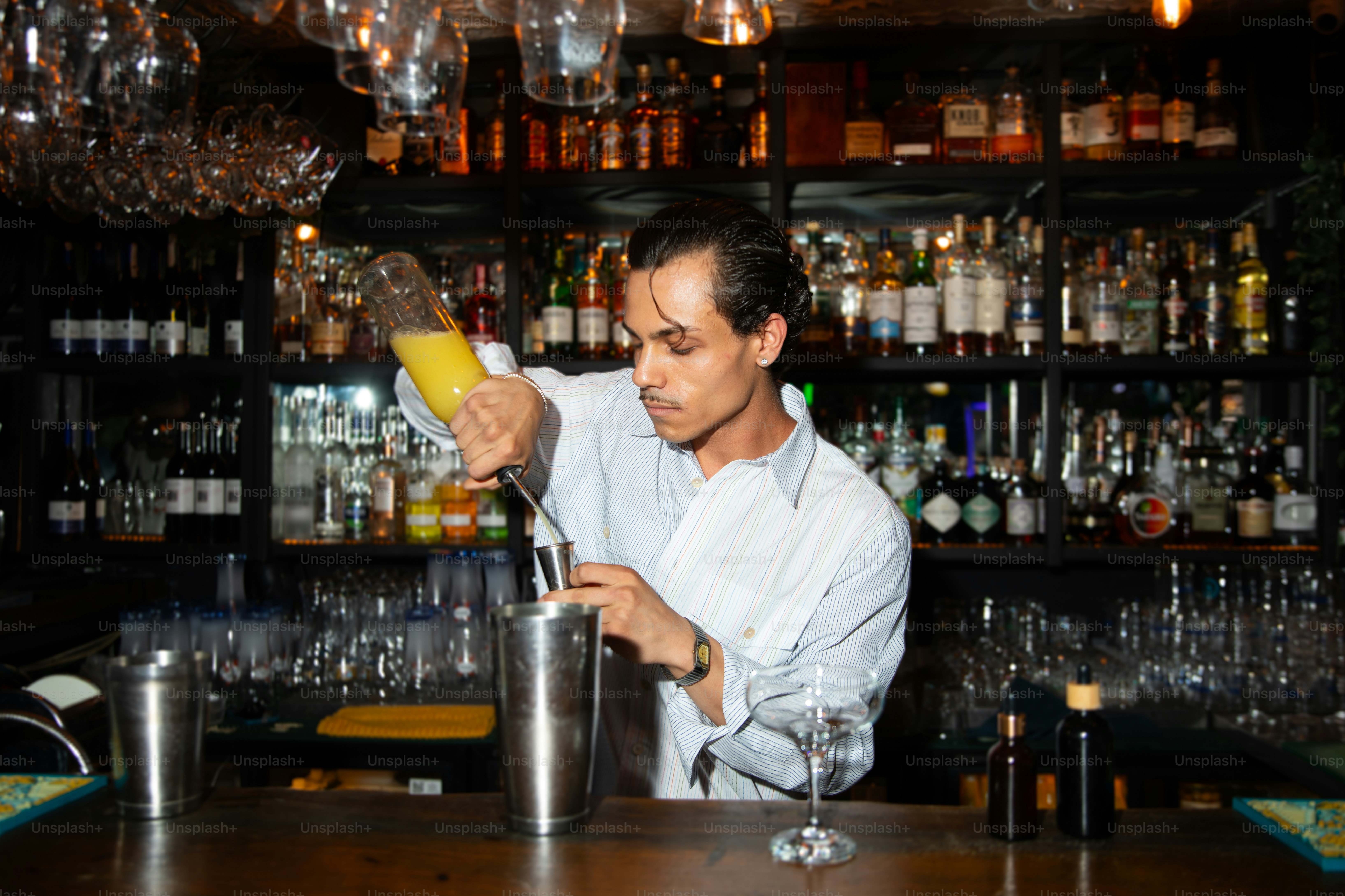 A bartender is making a cocktail at the bar.