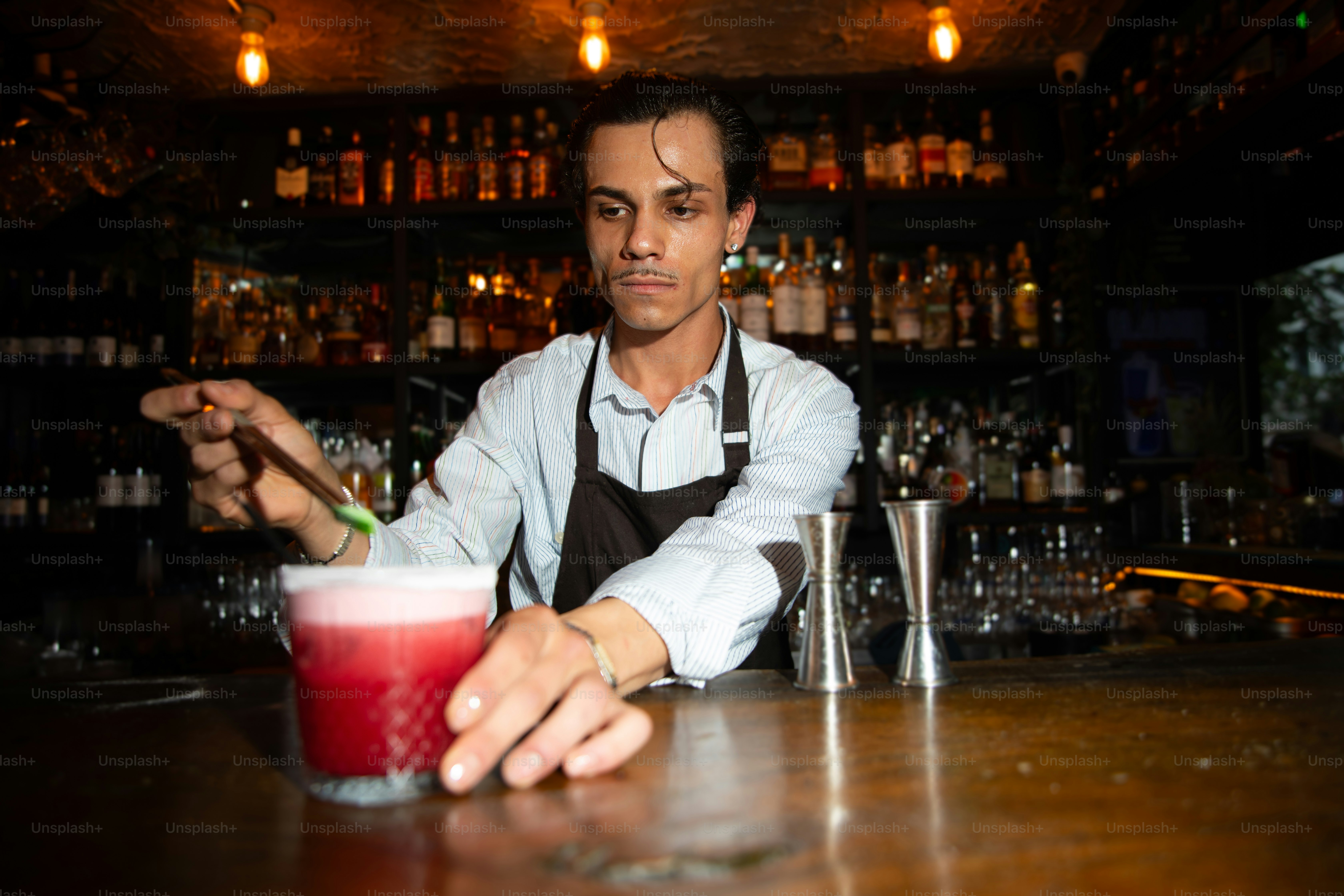 Bartender preparing a cocktail in a dimly lit bar.