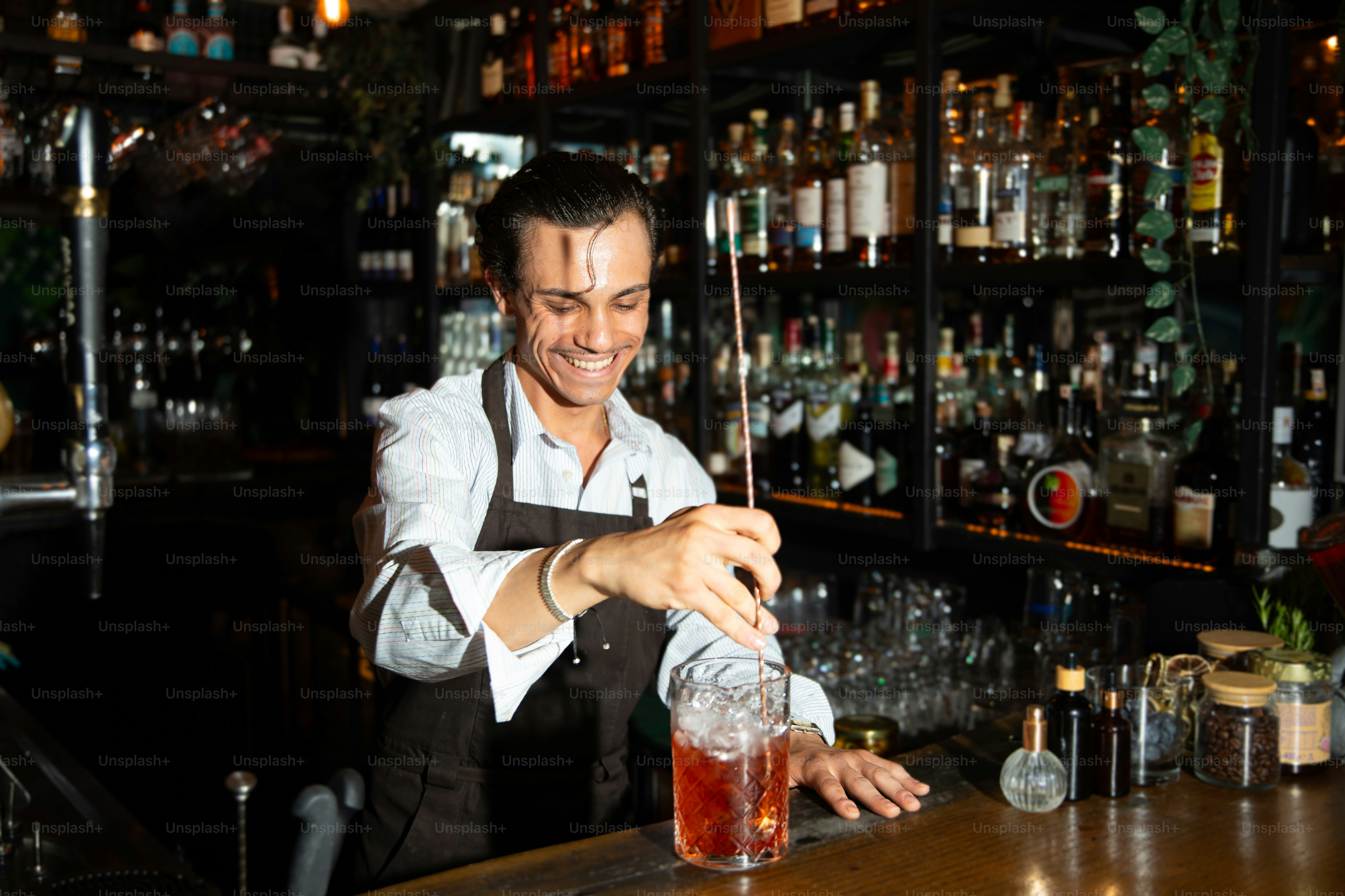 A smiling bartender prepares a drink in a bar.
