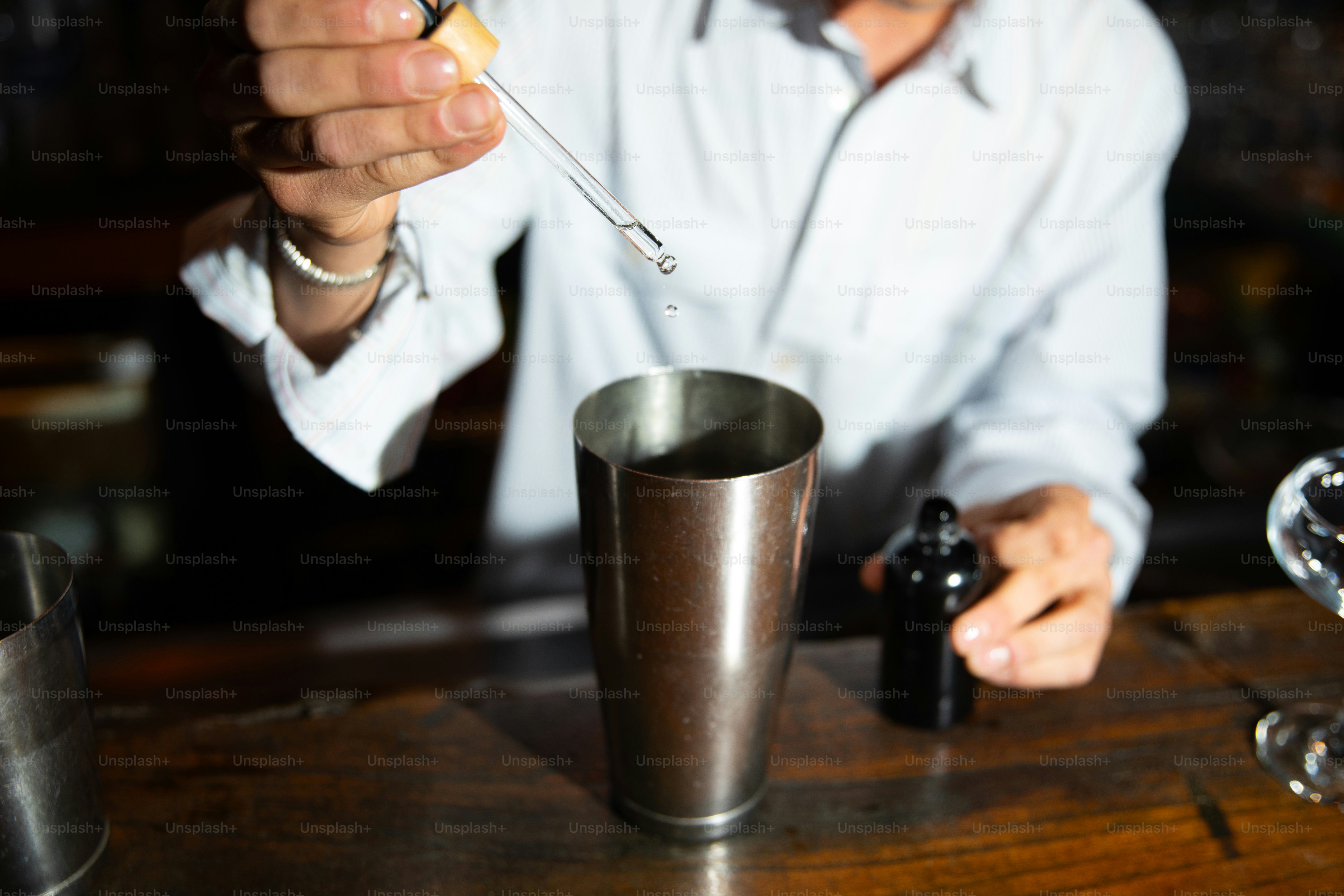 Bartender drizzles liquid into a cocktail shaker.
