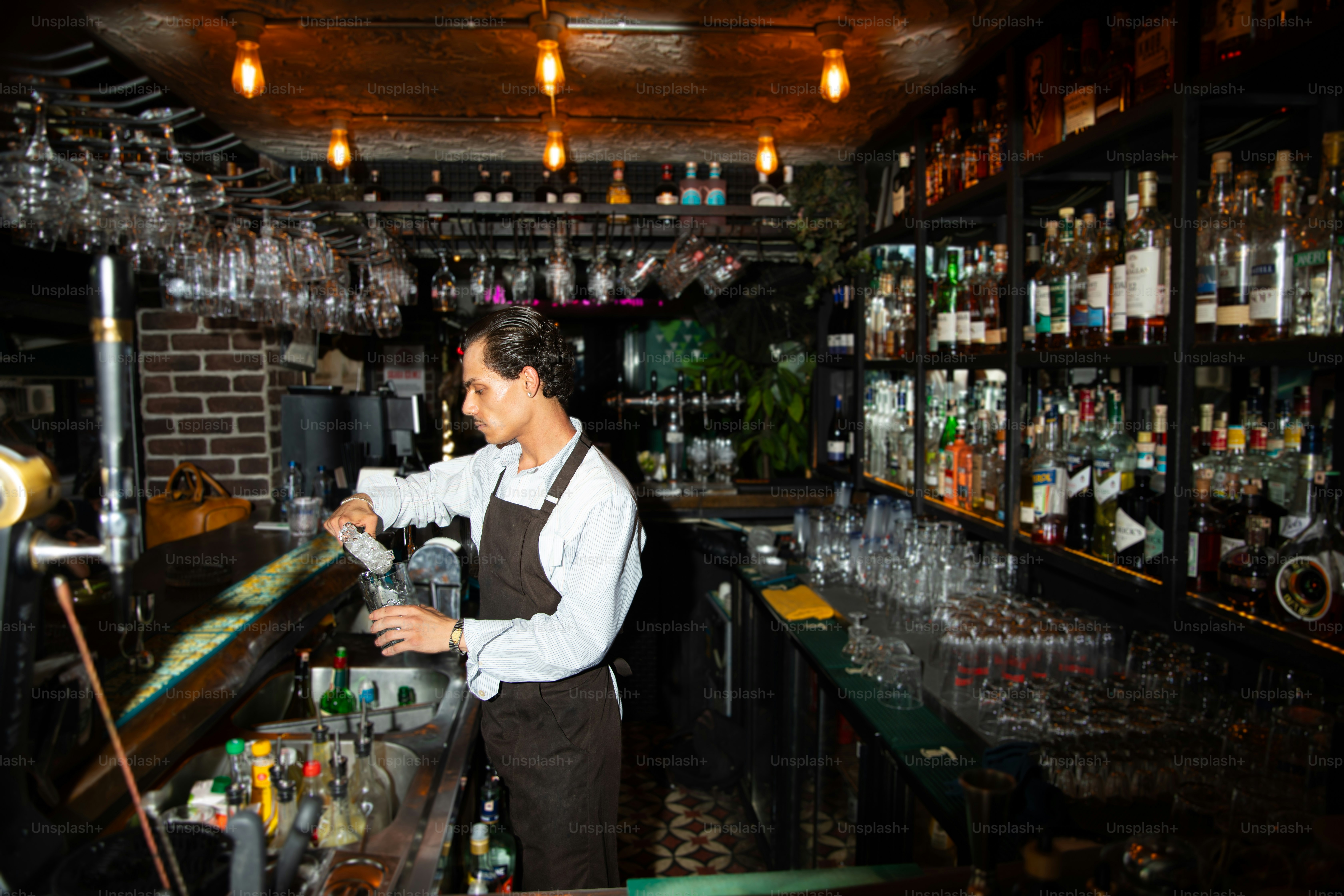A bartender works behind a well-stocked bar.