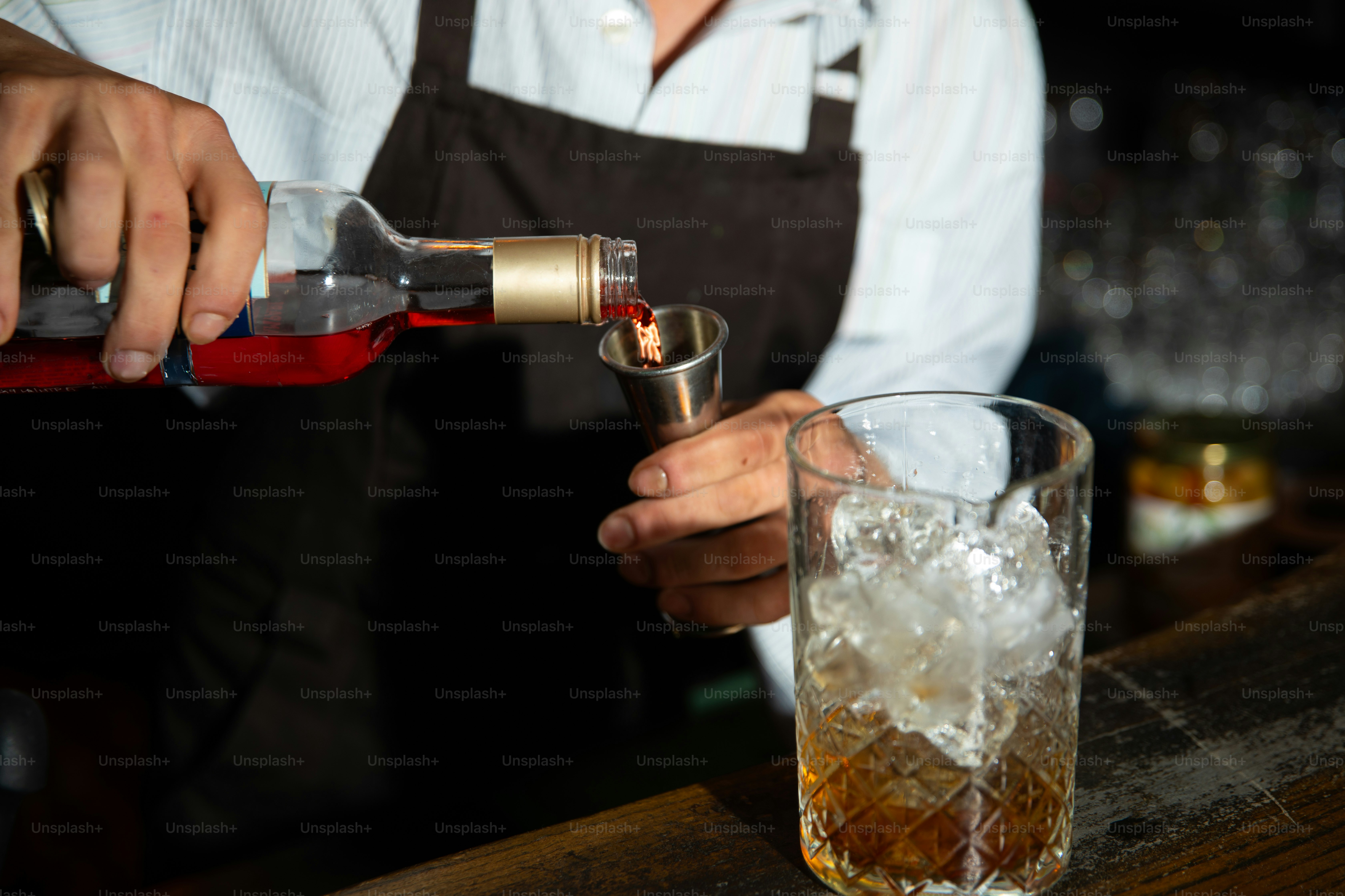 Bartender pours liquor into a cocktail glass.