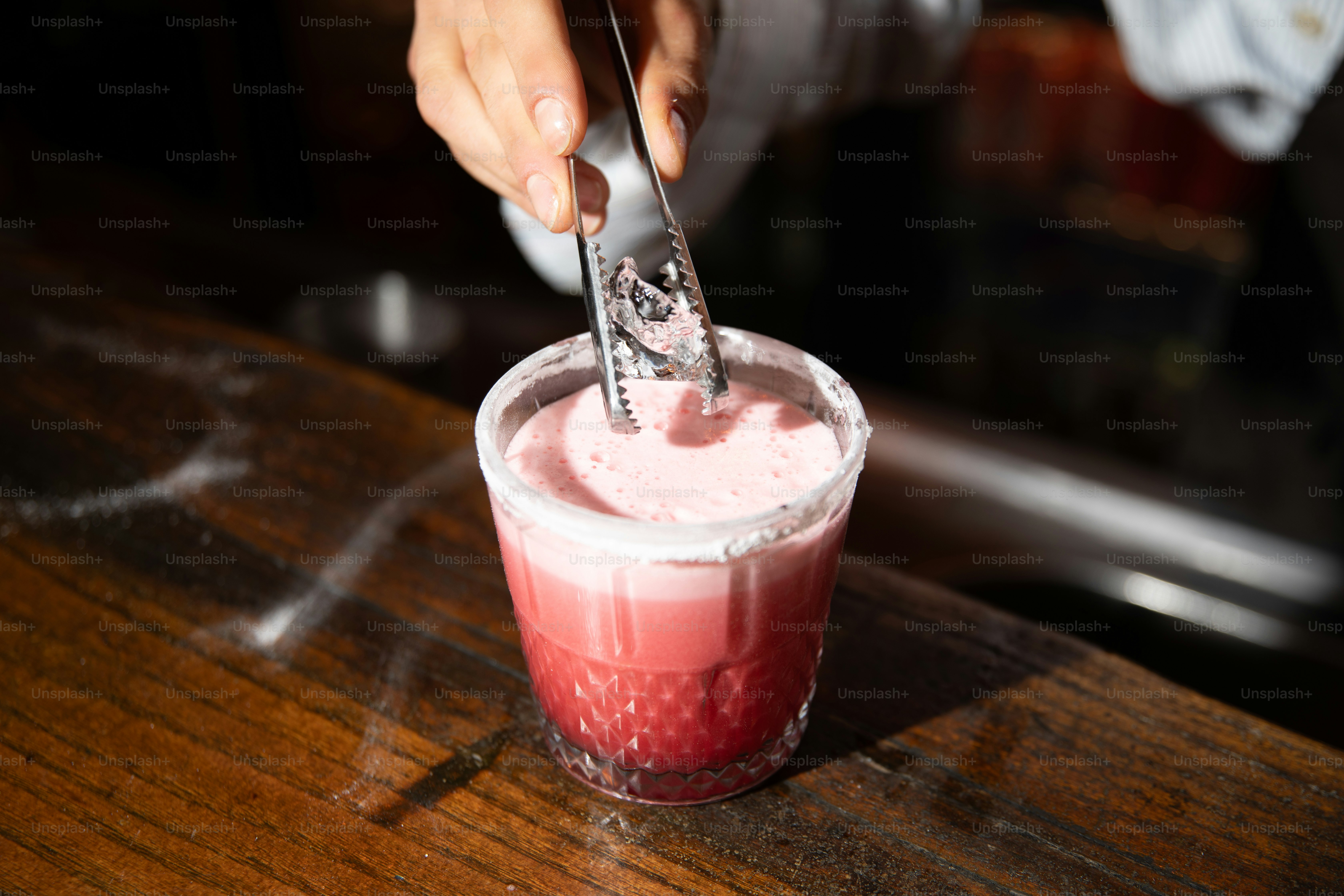 A bartender adding ice to a beautiful cocktail.