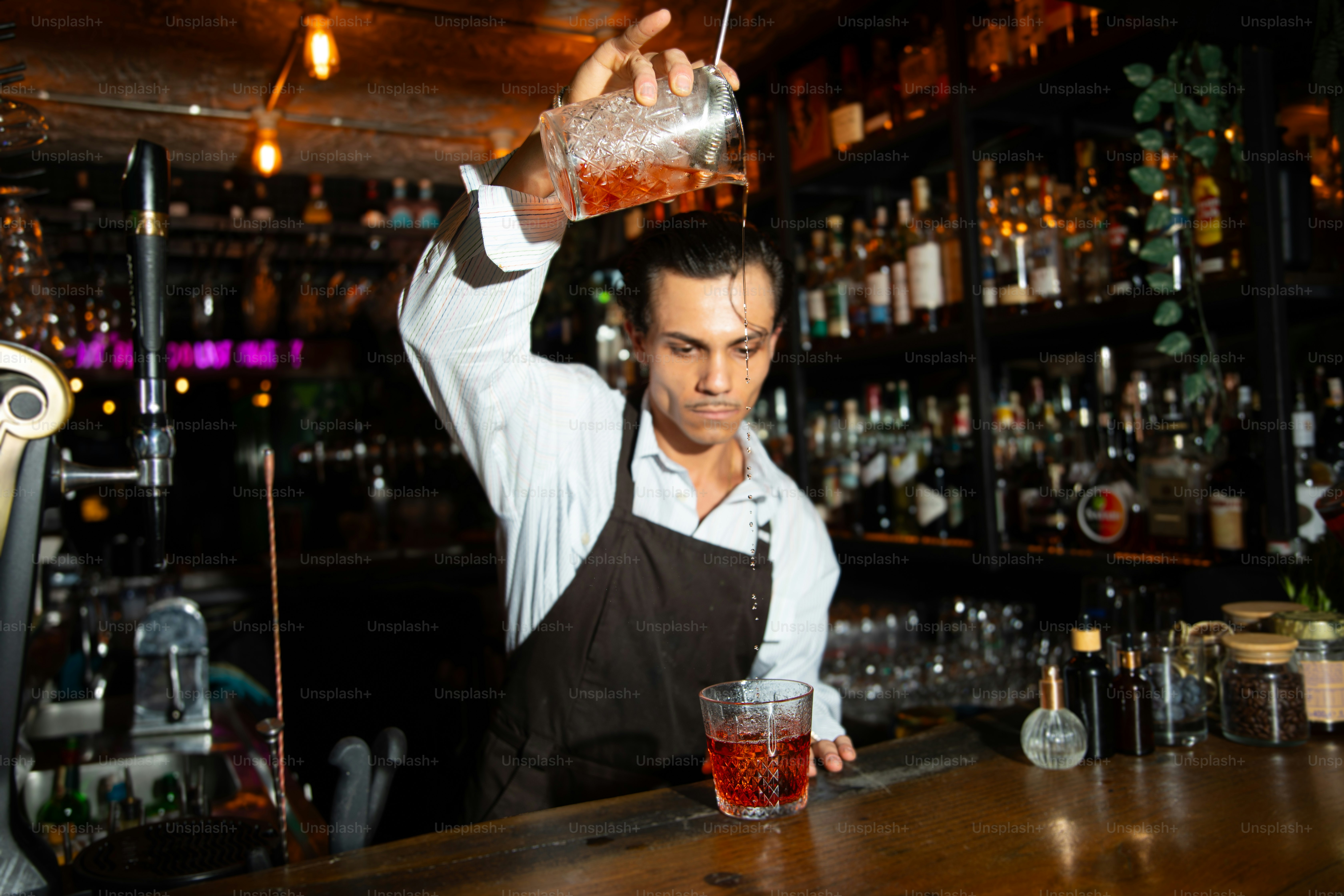 Bartender pours a drink into a glass.