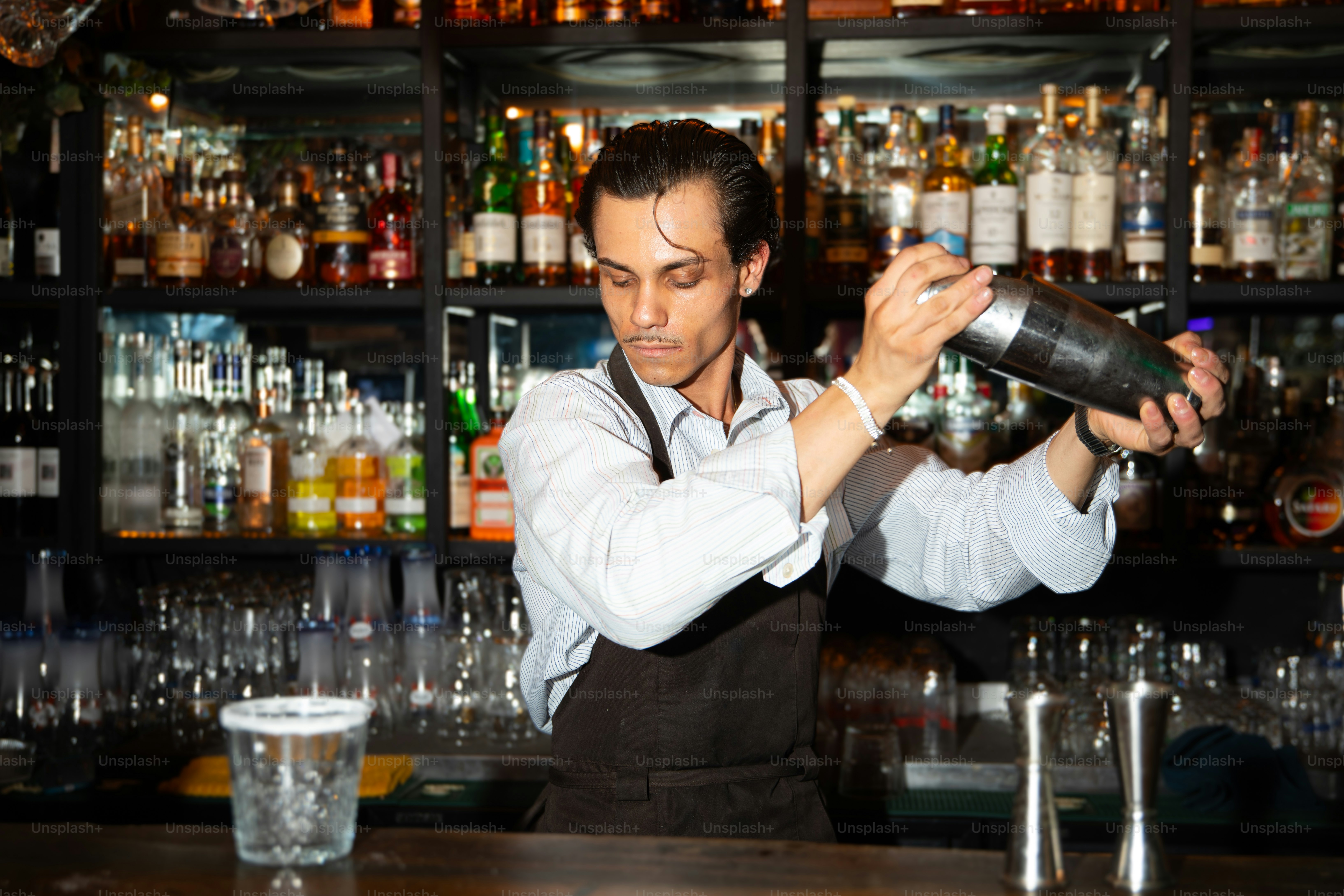 A bartender mixes drinks behind a well-stocked bar.