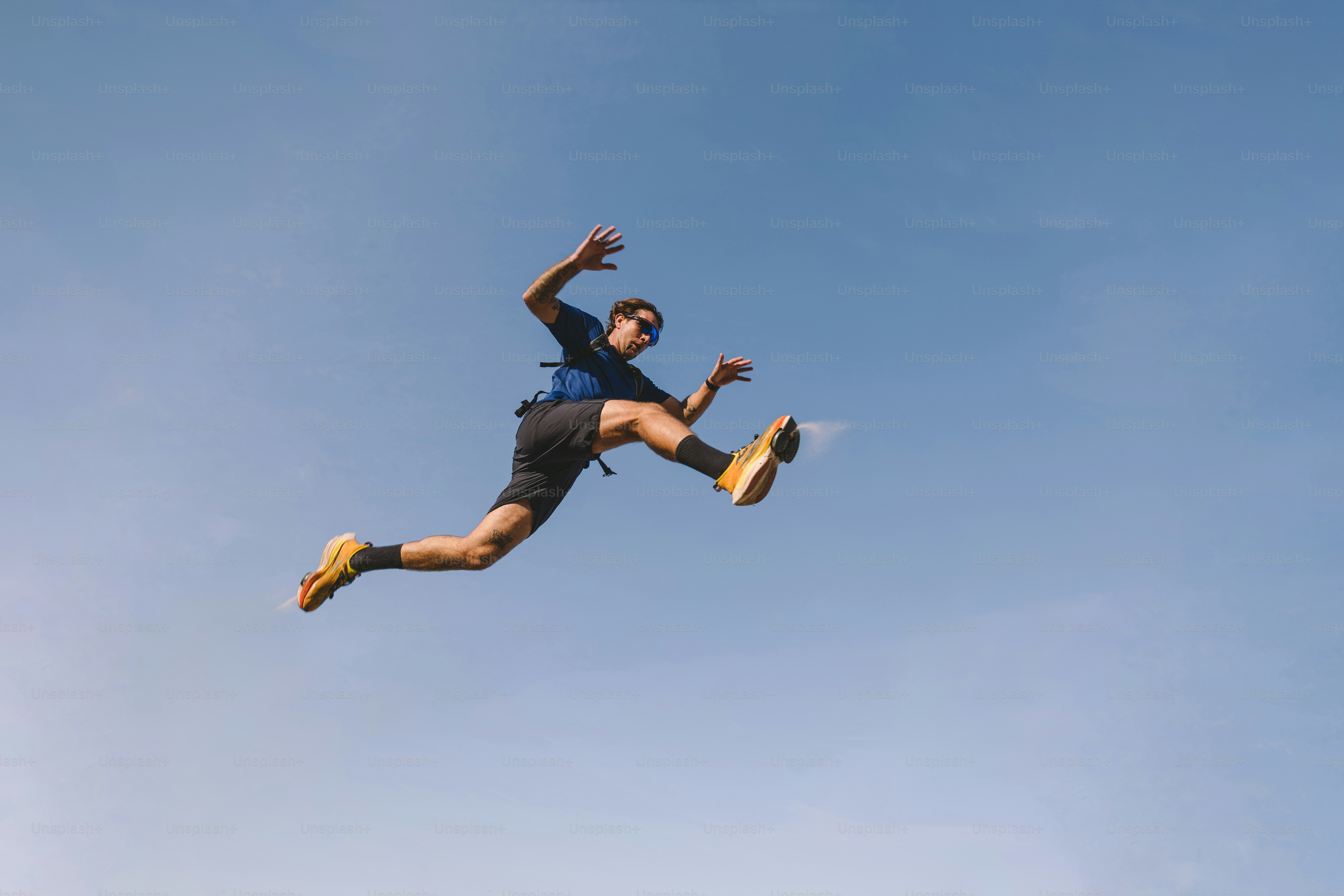 Man leaps through the air against a blue sky.