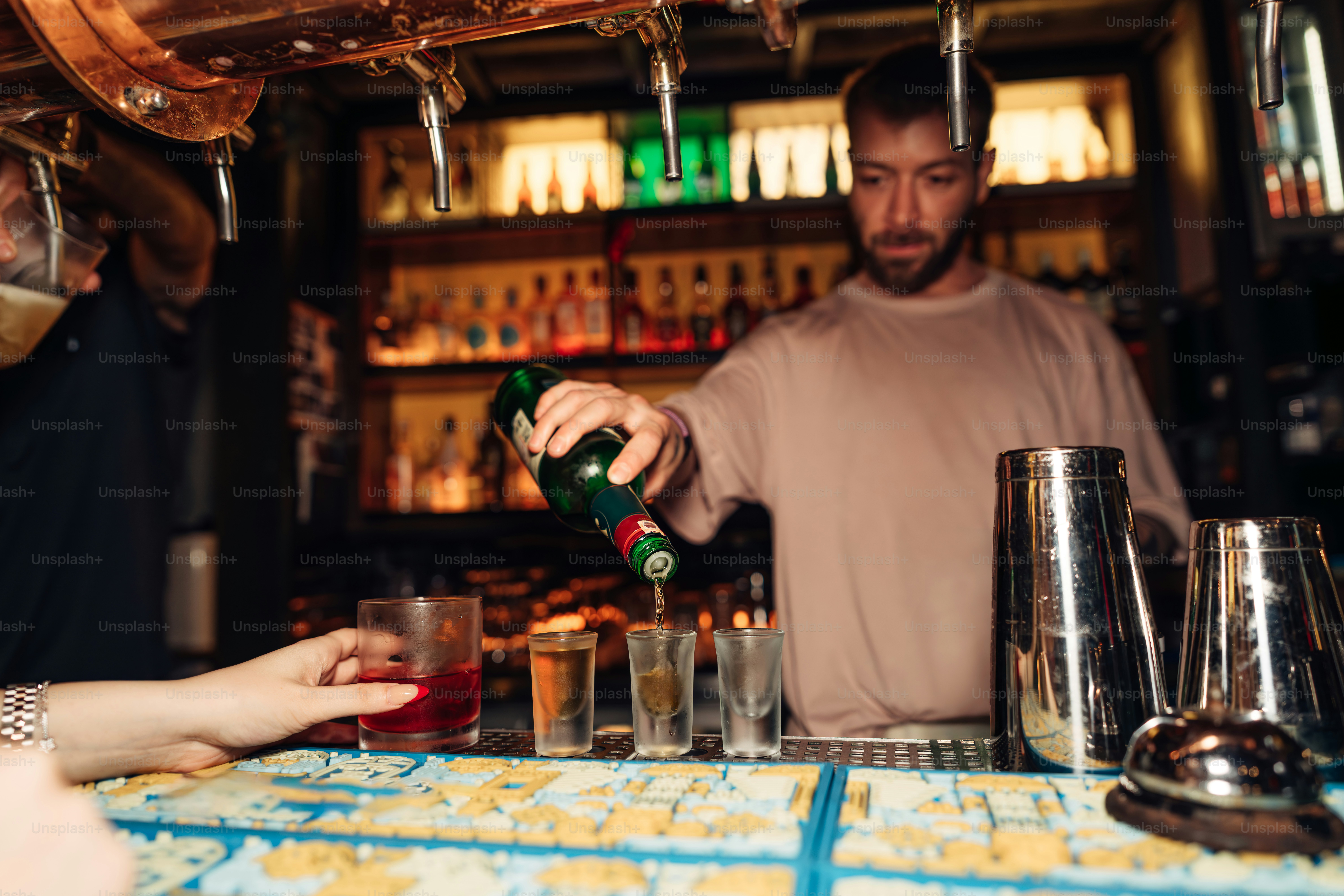 Seorang bartender sedang menuangkan tembakan ke sebuah bar.