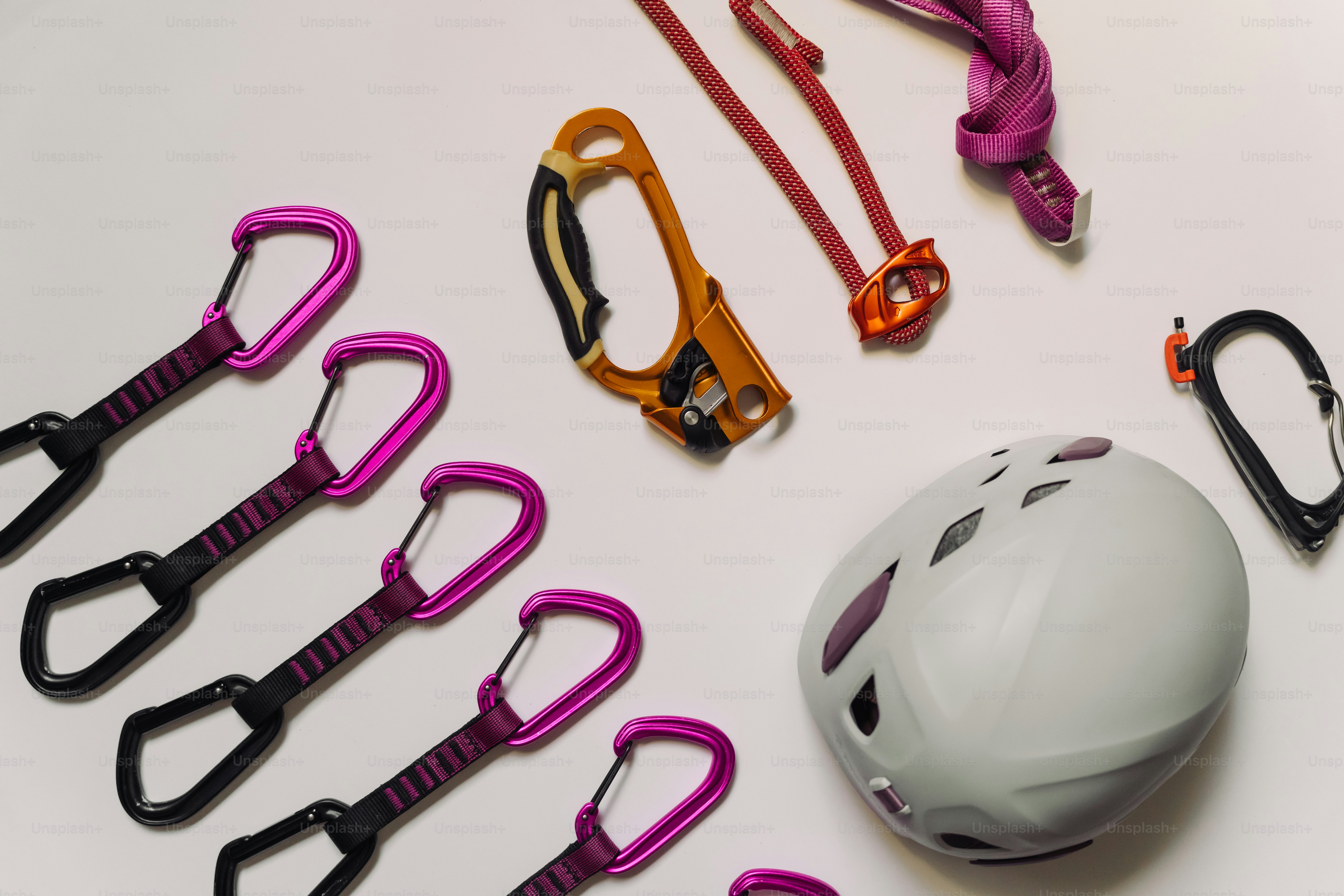 Equipo de escalada dispuesto sobre una superficie blanca.