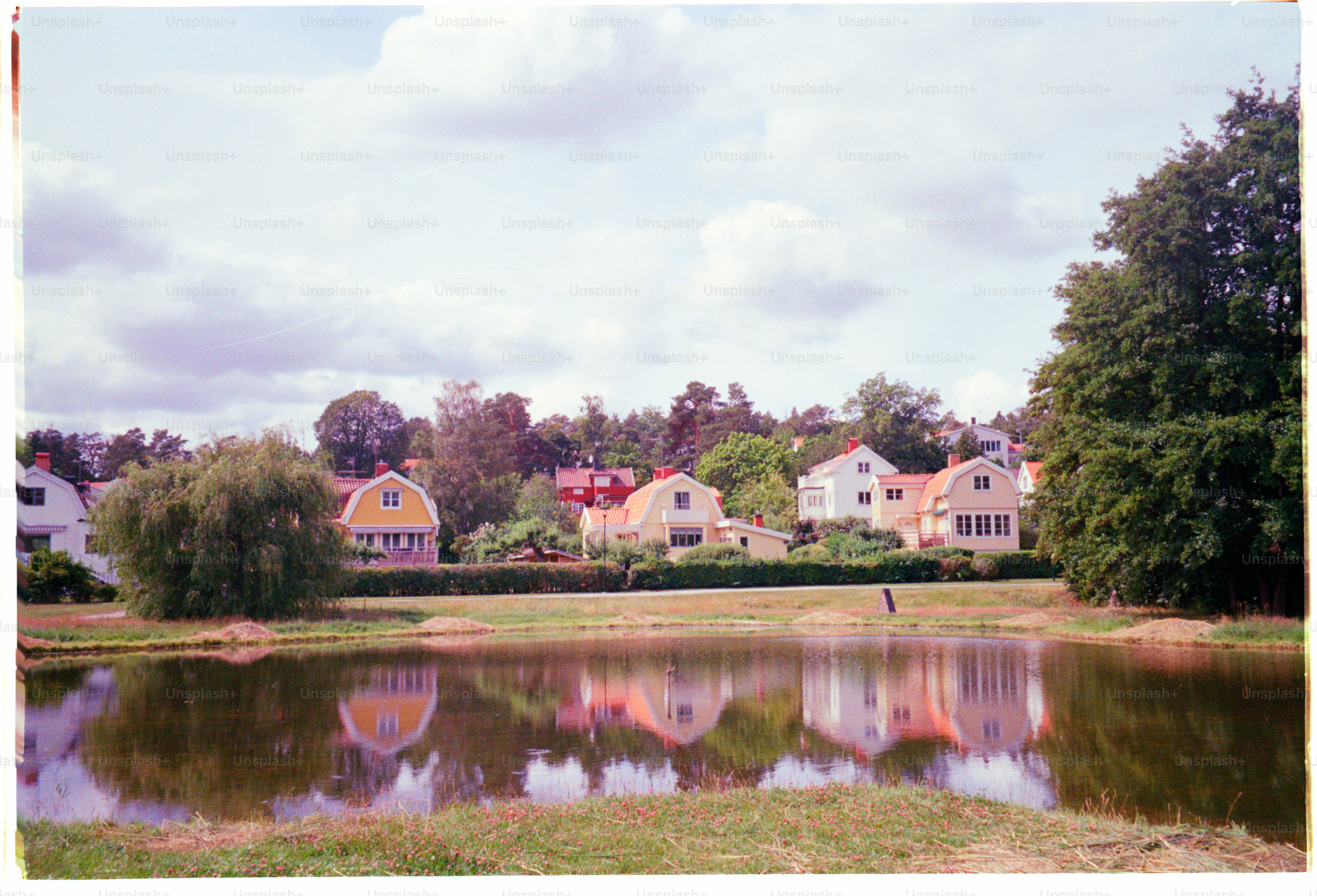 Houses are reflected in the water of a pond.