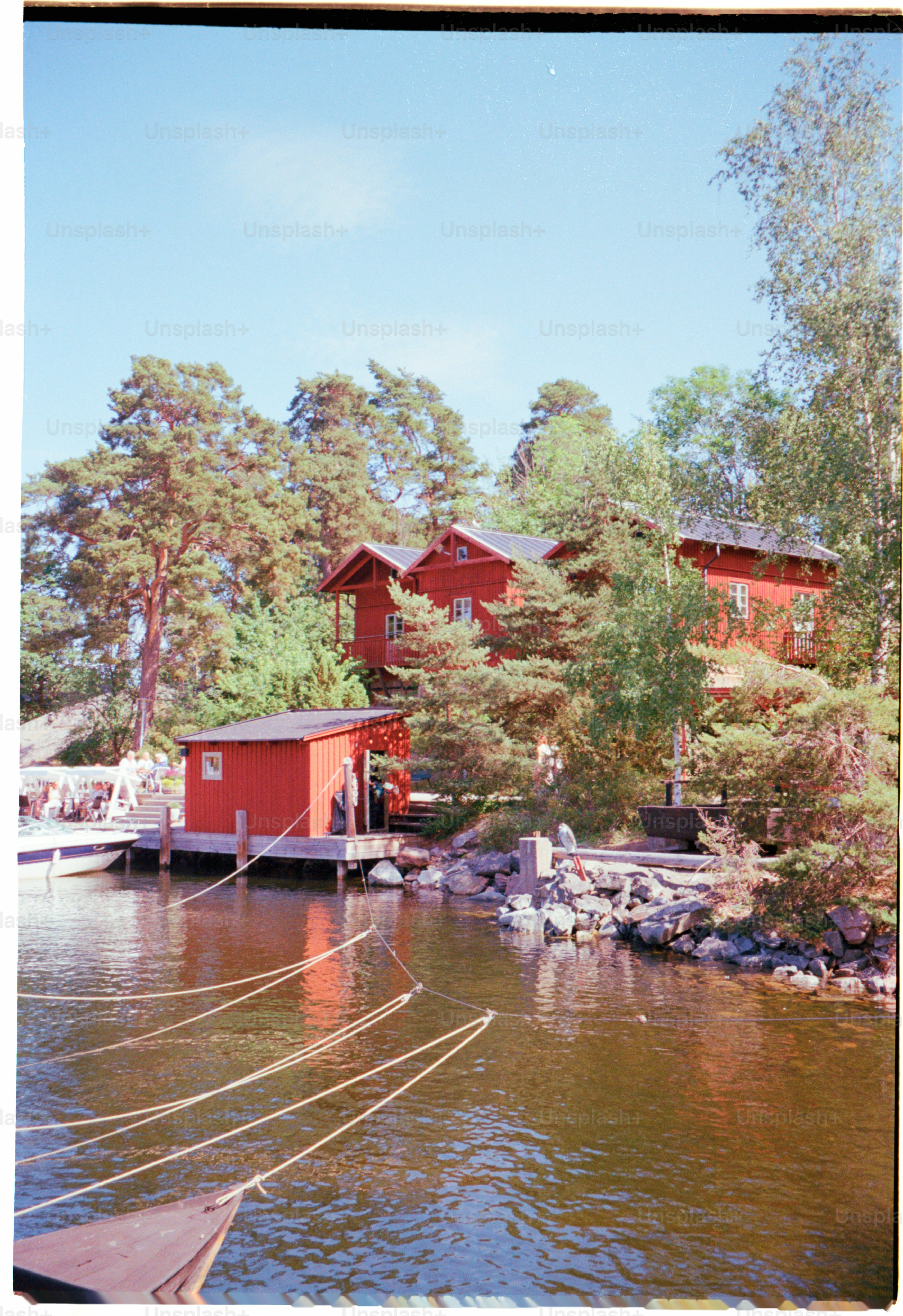 Red wooden houses sit by the calm water.