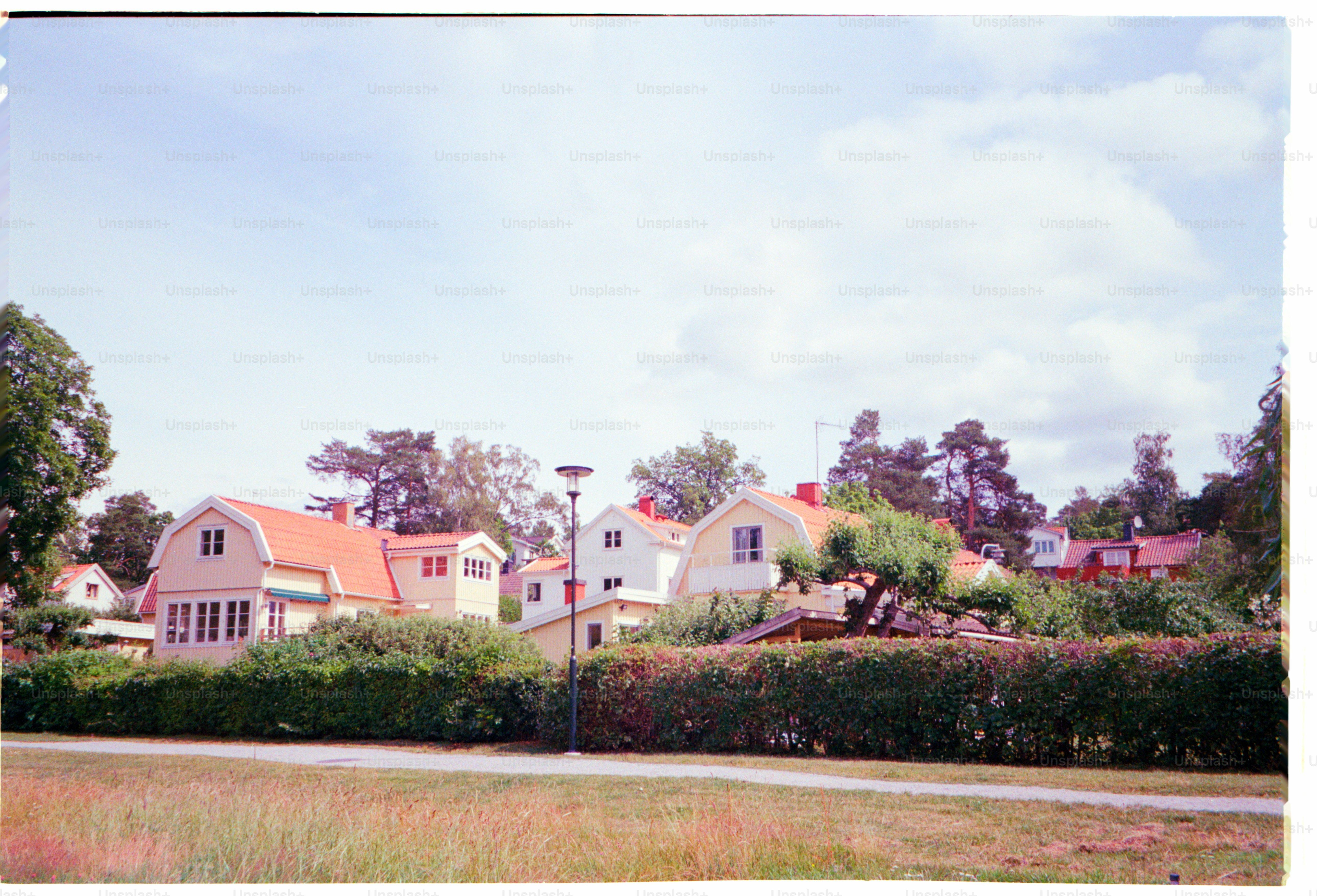 Houses with orange roofs stand under a cloudy sky.