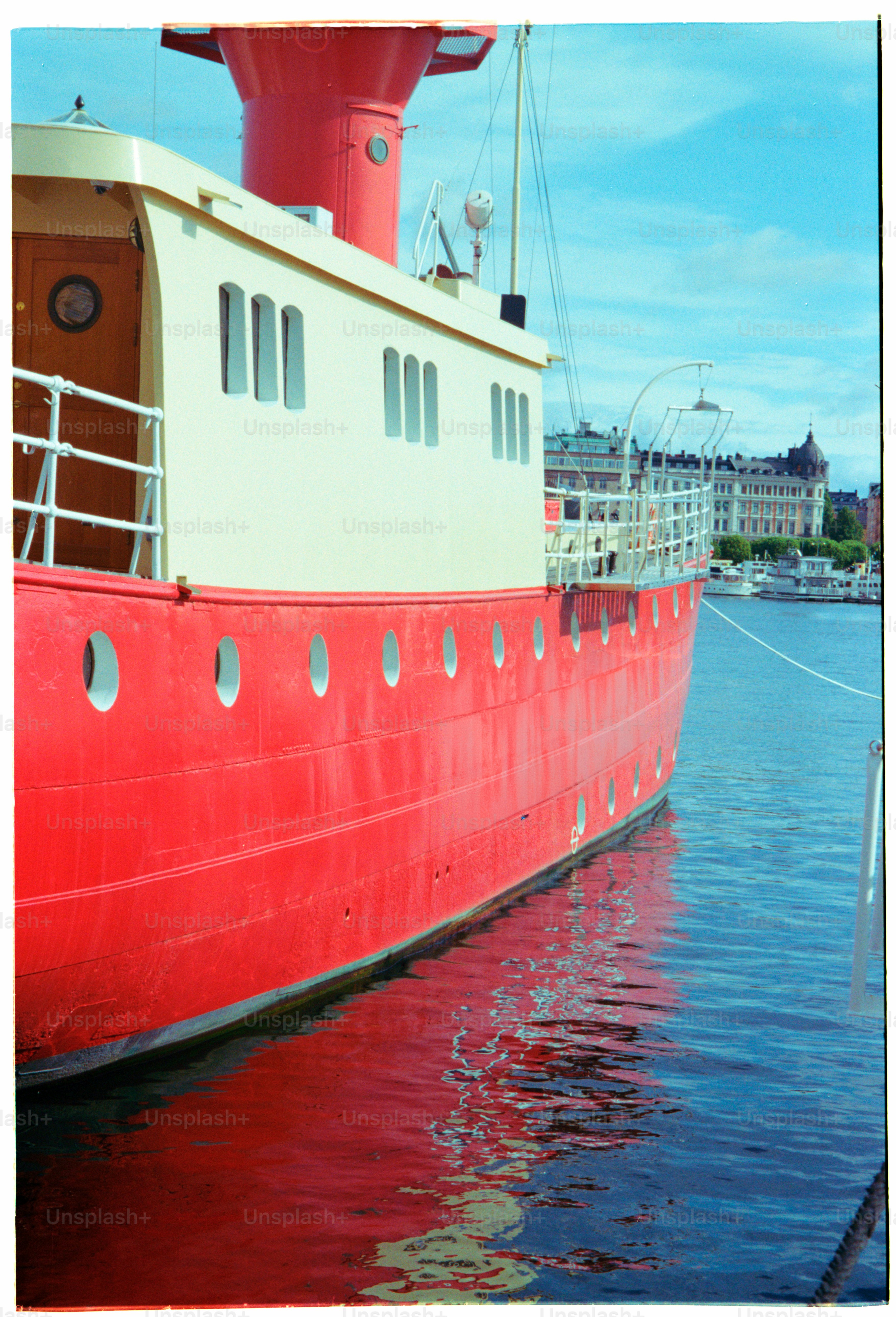 A red and white boat reflects in the water.