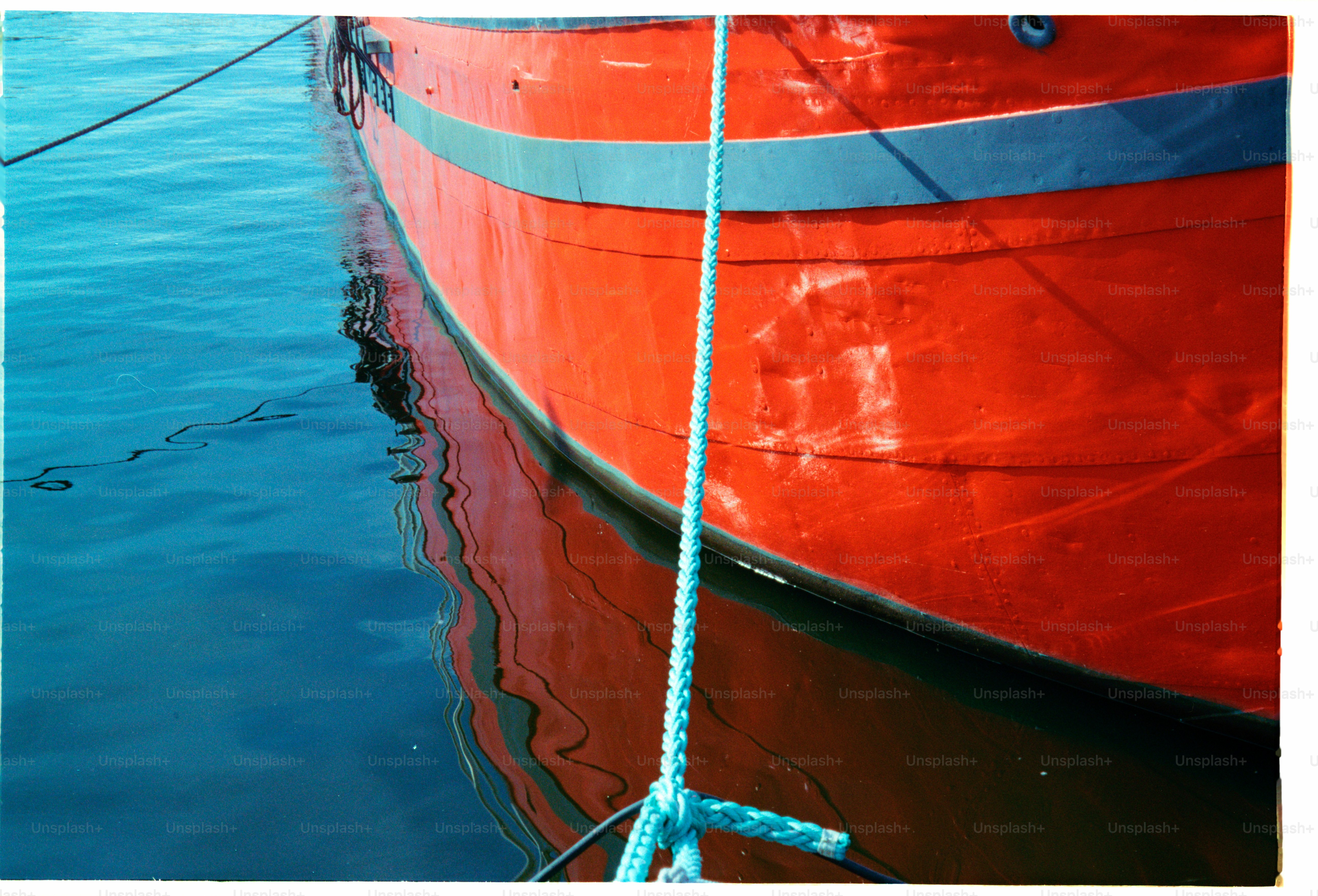 Rotes Boot spiegelt sich im stillen, blauen Wasser.