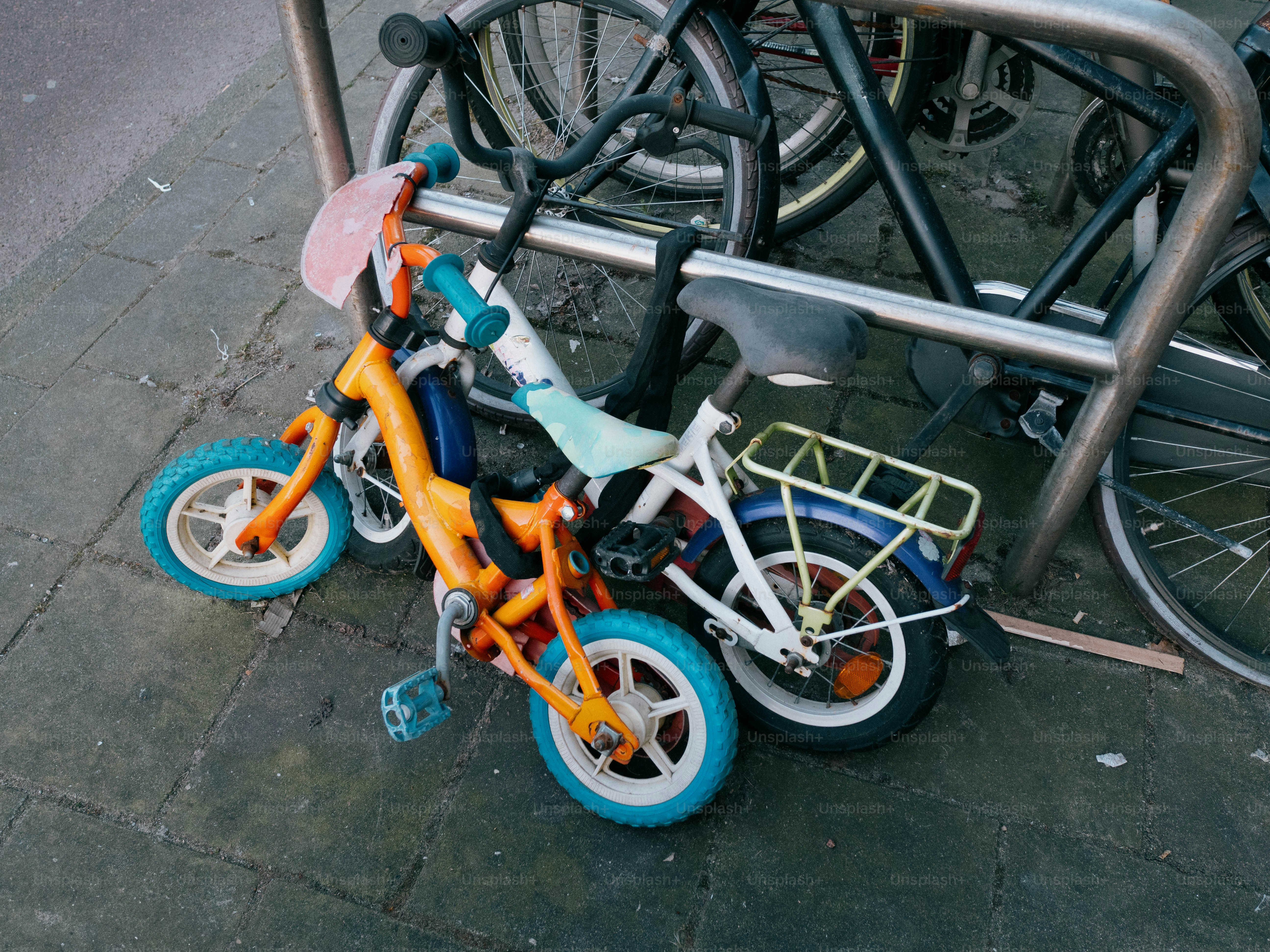 Two small bikes are leaning against a bike rack.