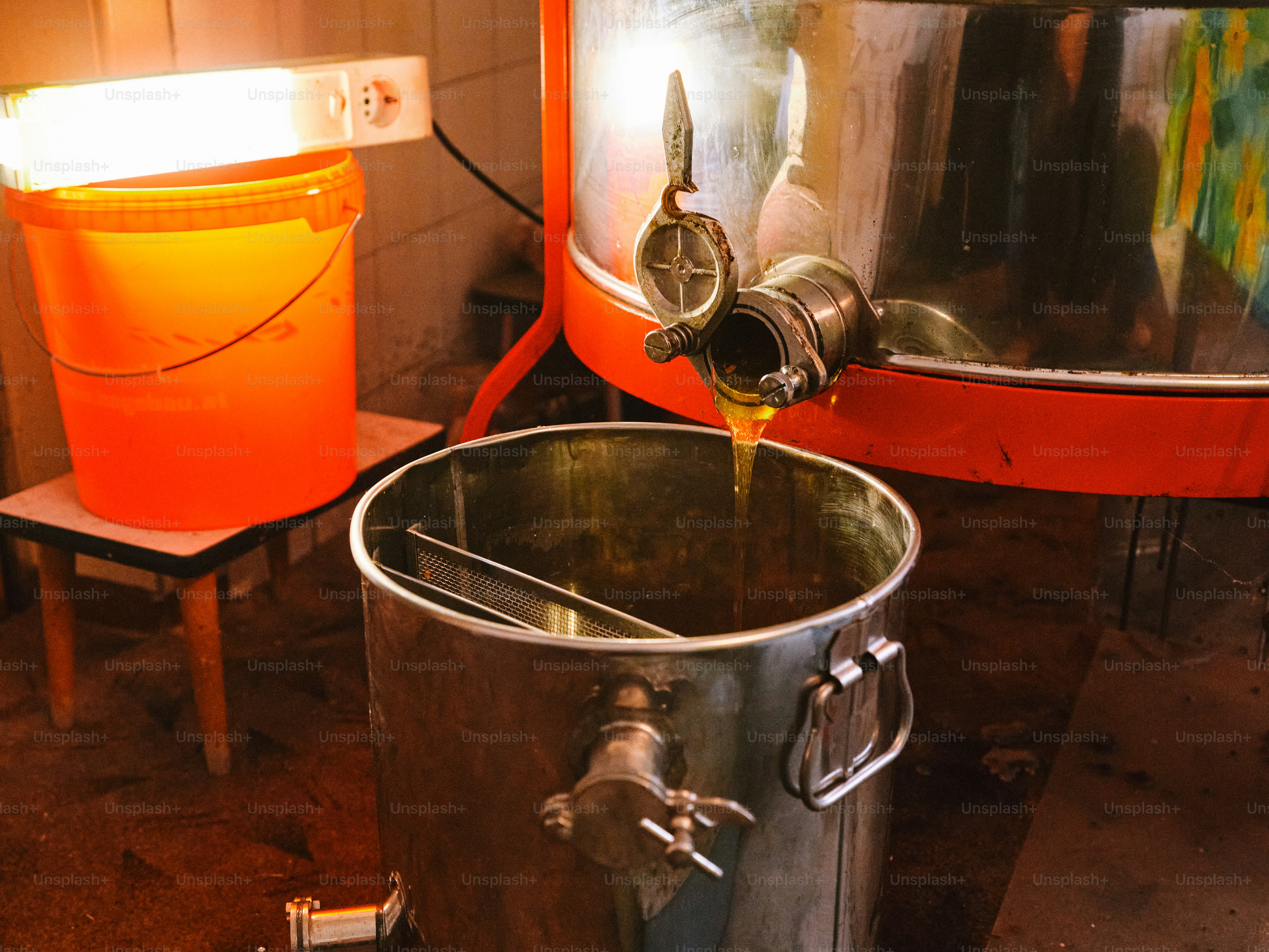 Honey is extracted from a large metal container.