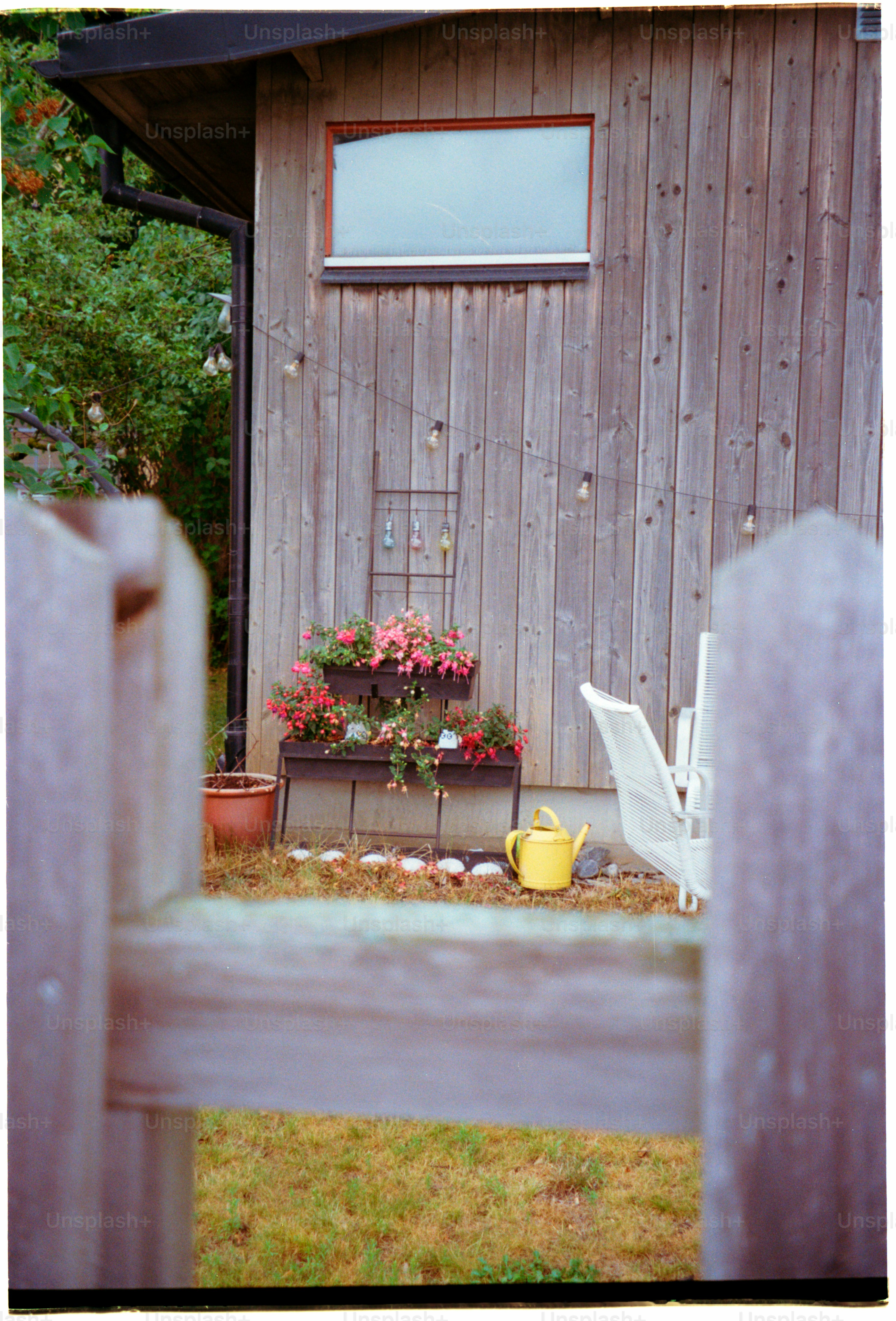 Wooden house exterior with flowers and a yellow watering can.