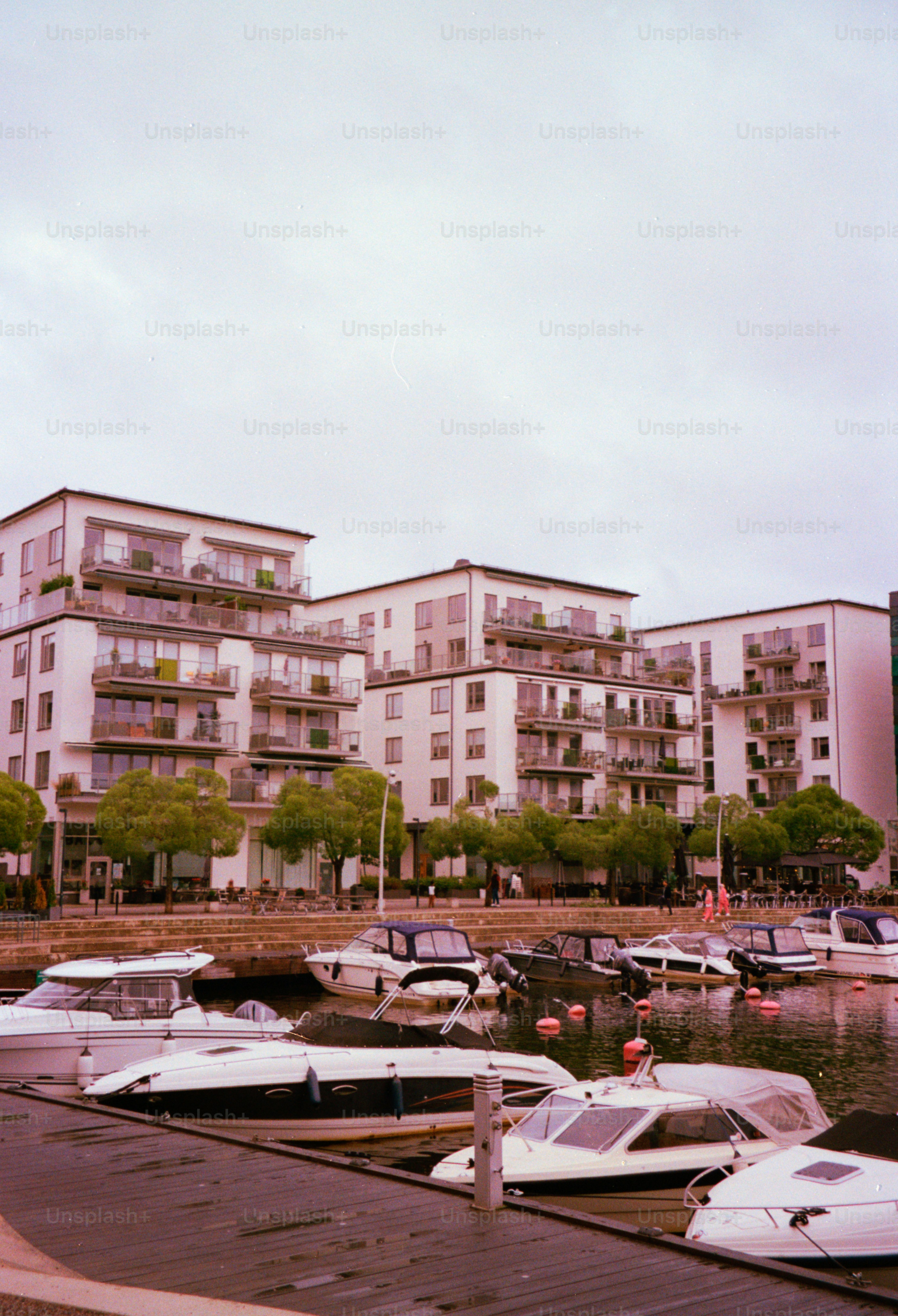 Boats are docked near apartments on a cloudy day.