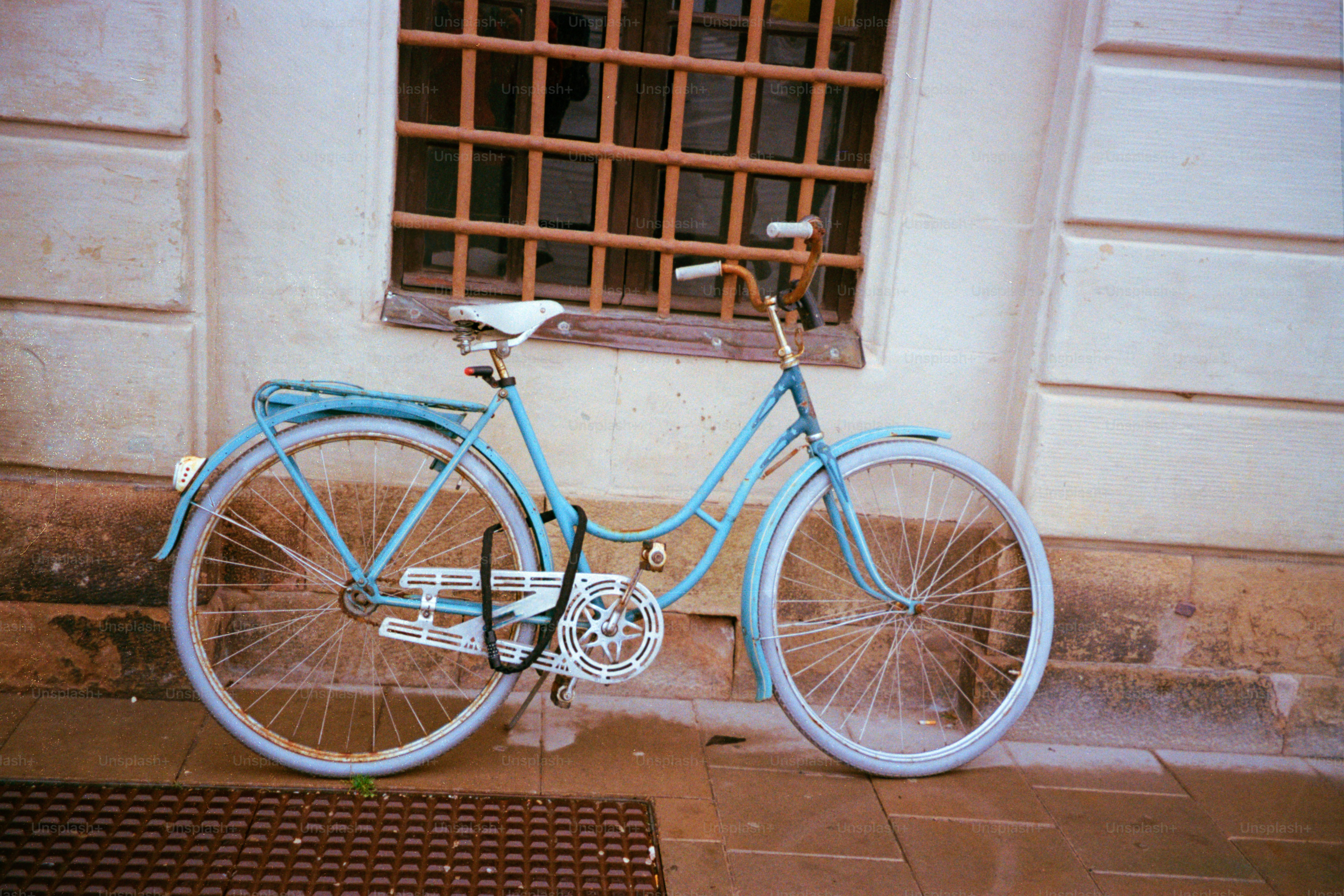 A blue bicycle rests next to a building.