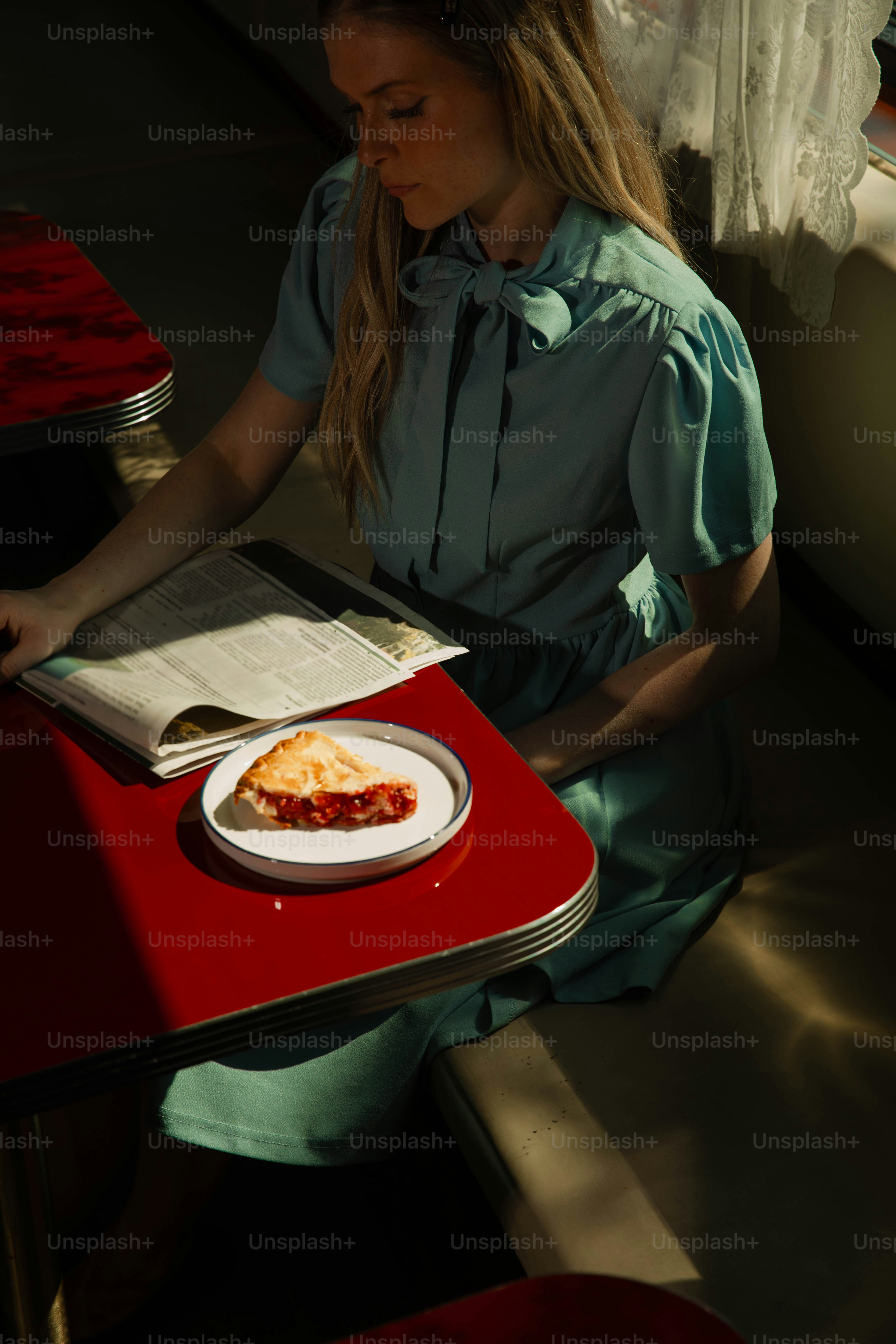 Woman eats pie at a diner, reading a menu.