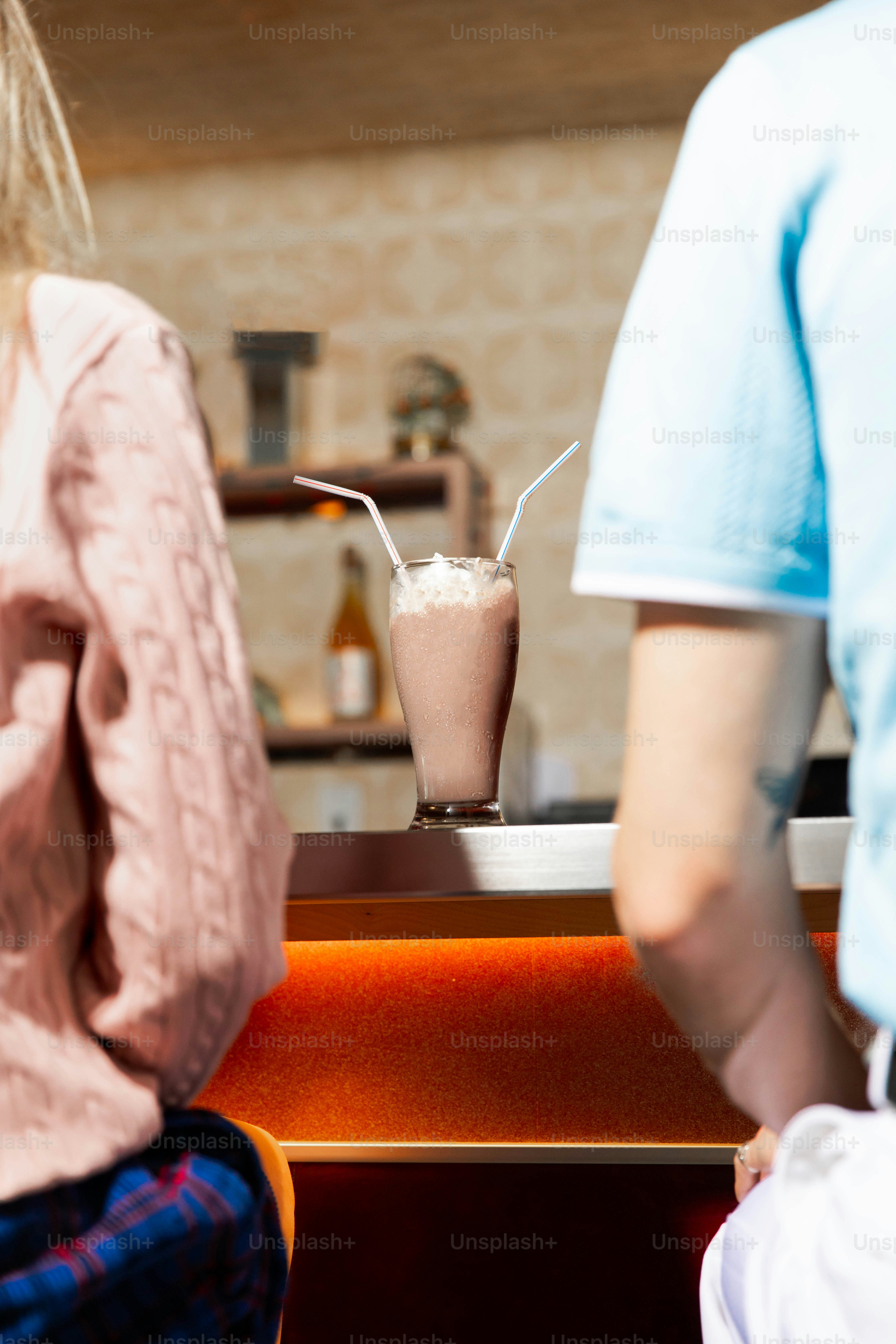 Couple shares a milkshake at the diner counter.