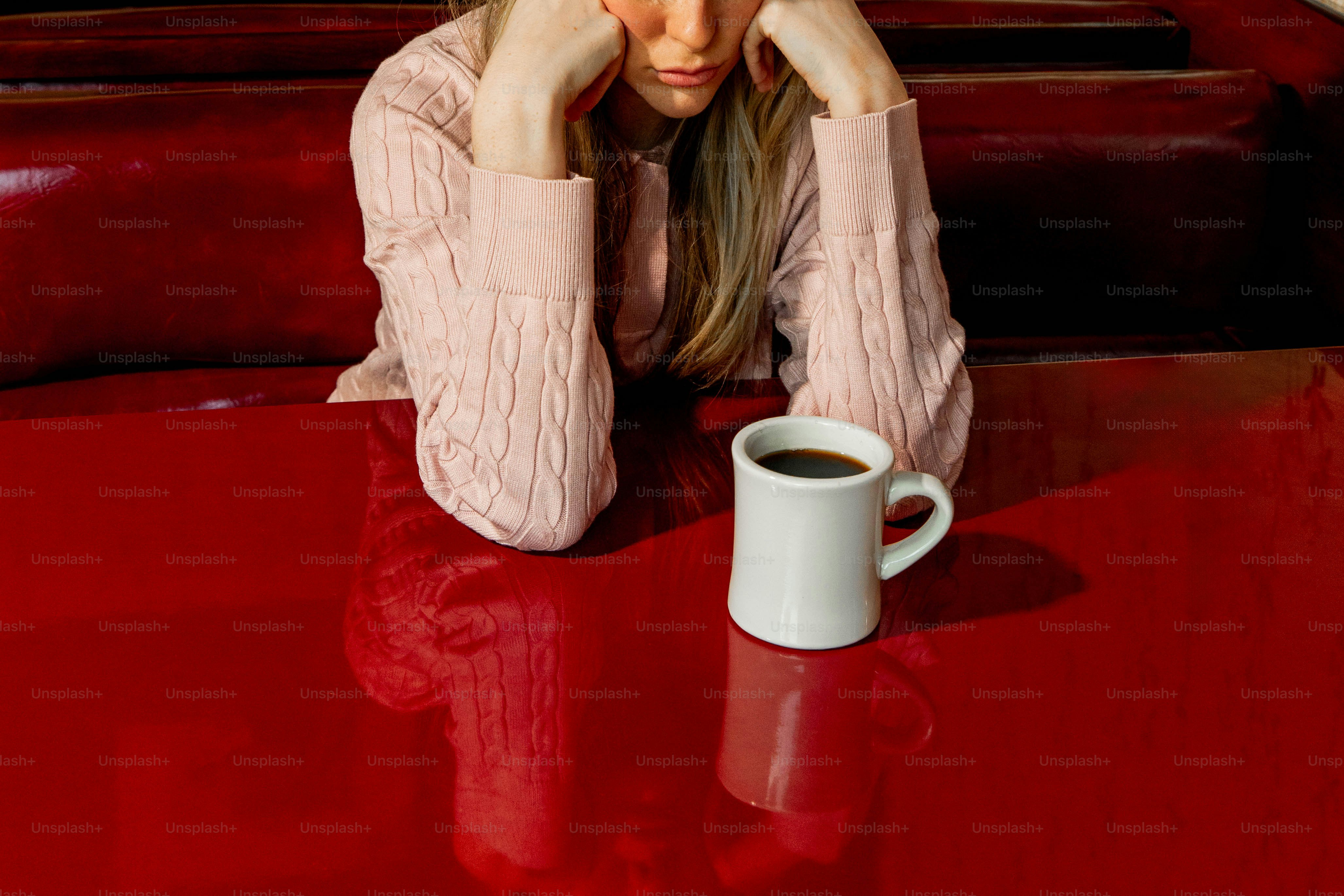 Woman looking down with coffee on the table.
