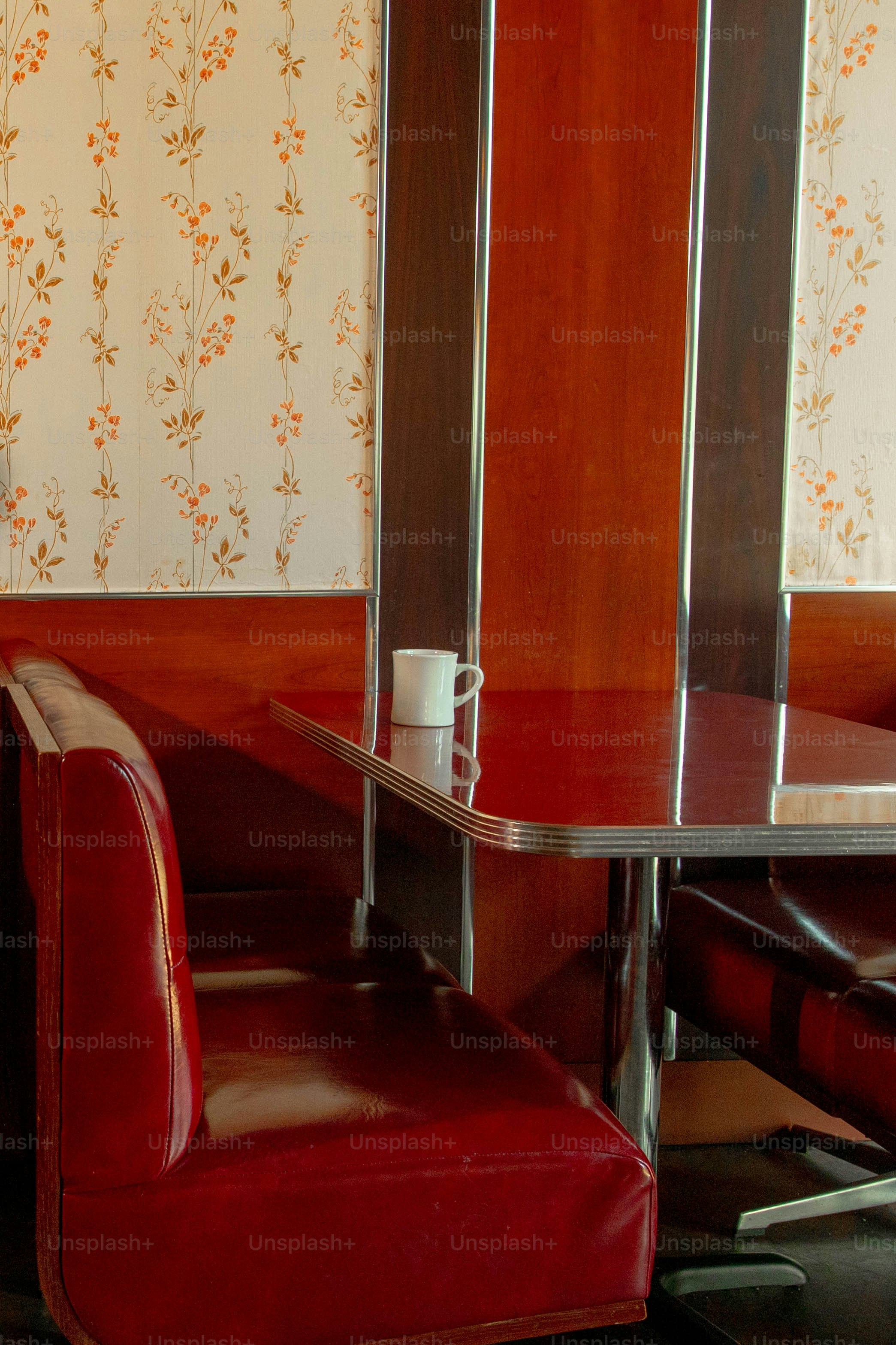 A diner booth: cozy red seat, table, and wallpaper.