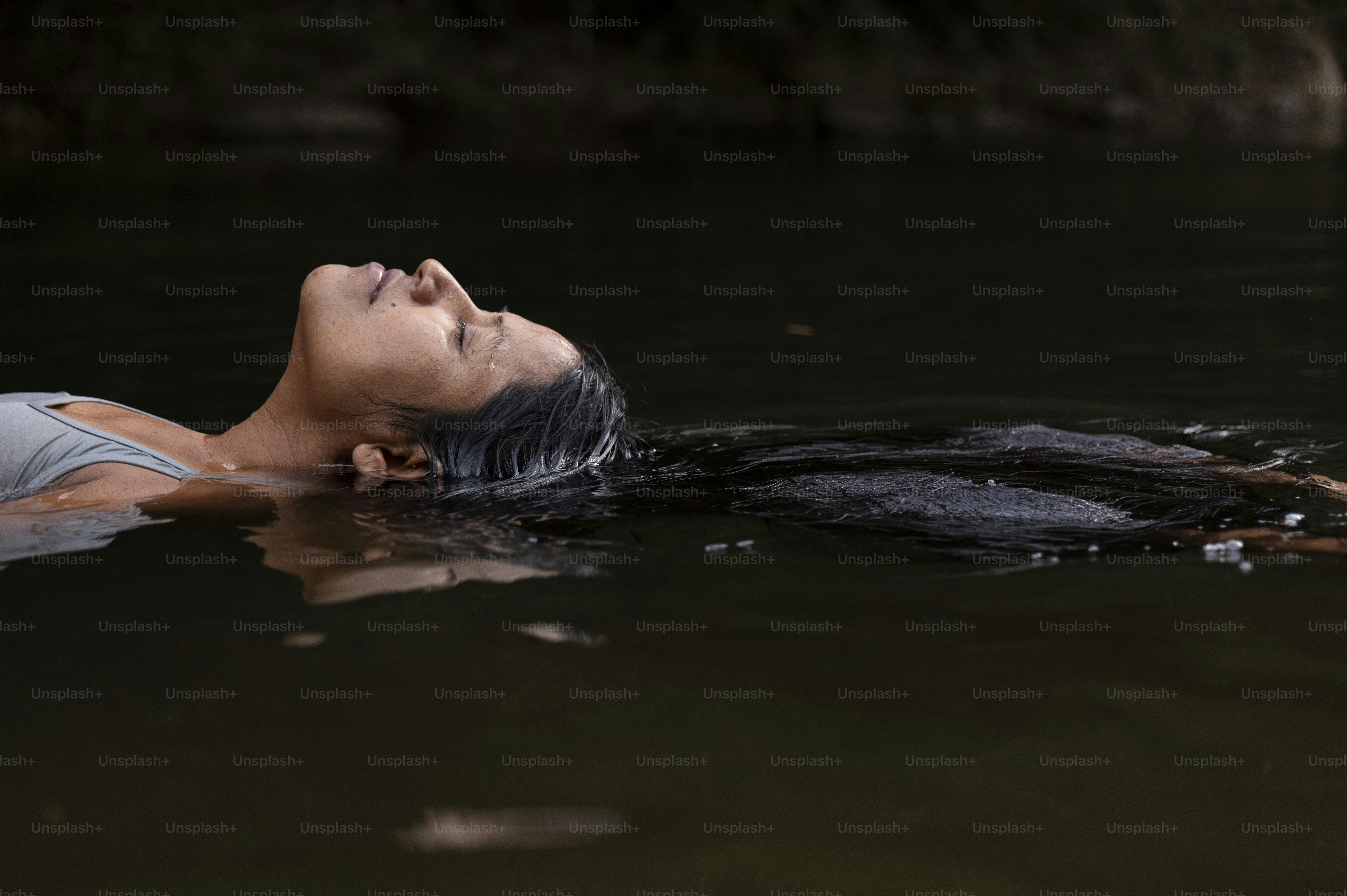 暗い水の中にリラックスして浮かんでいる女性。