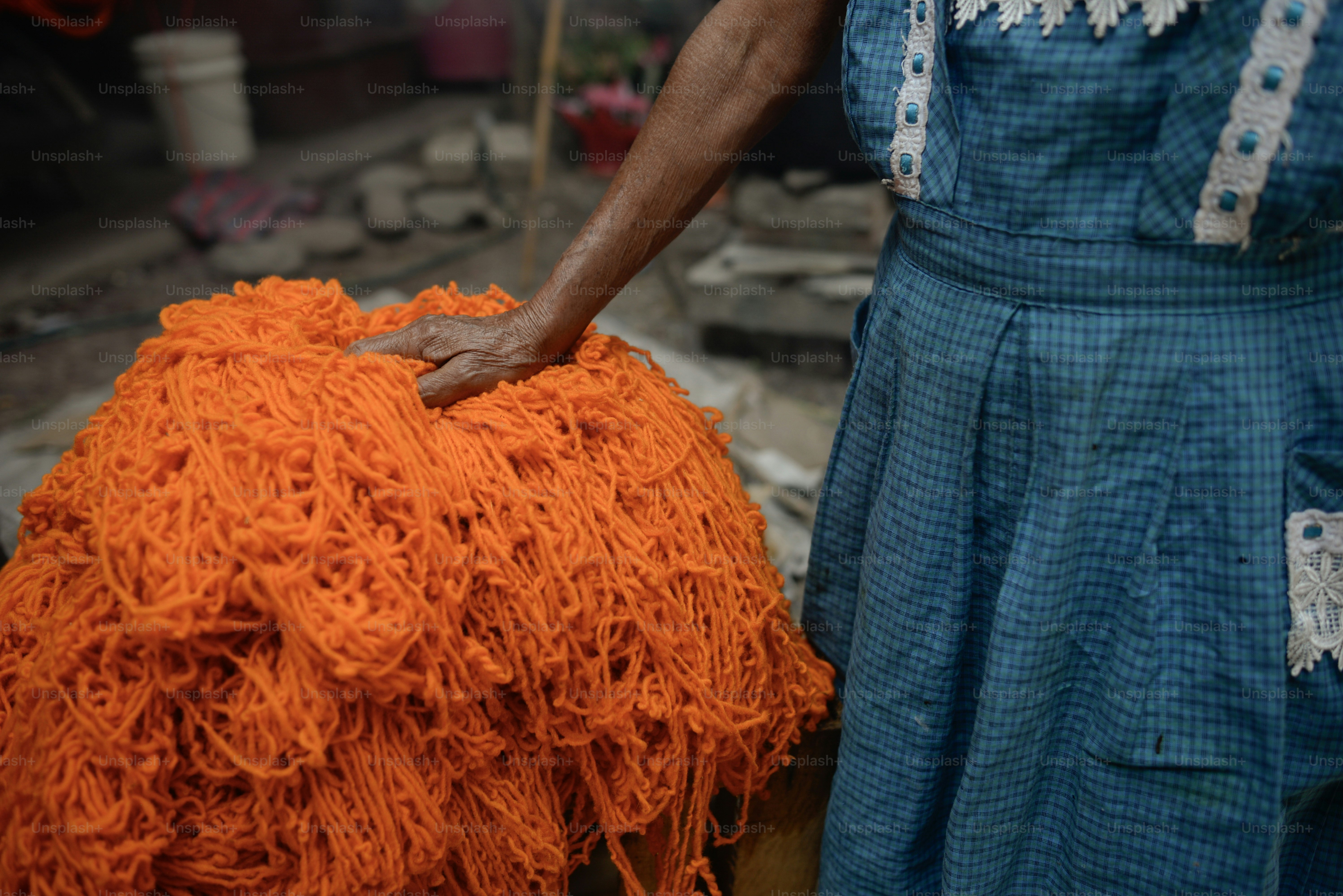 オレンジ色の糸の大きな山の上に女性の手。