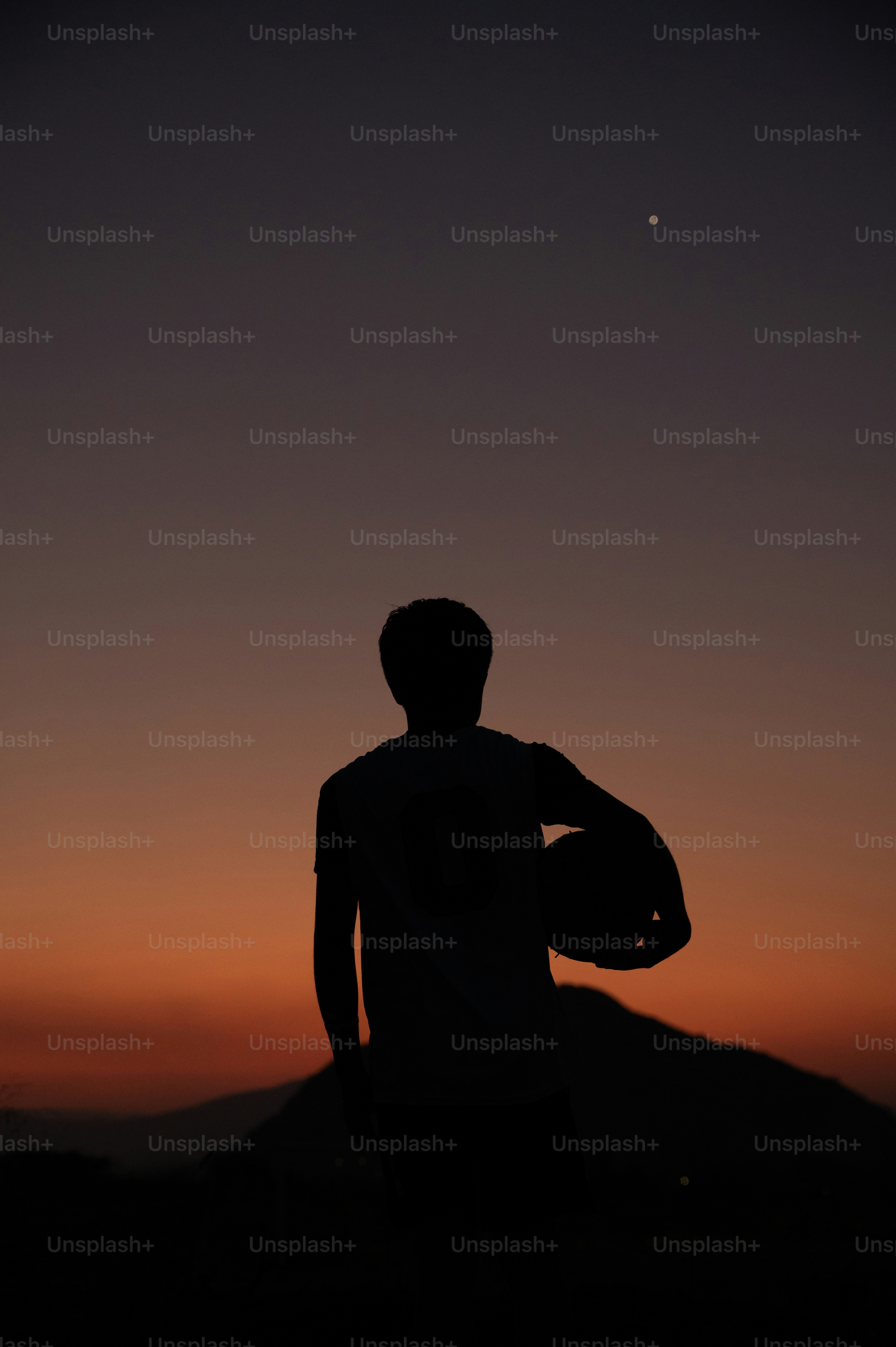 Silhouette of person holding a helmet at sunset