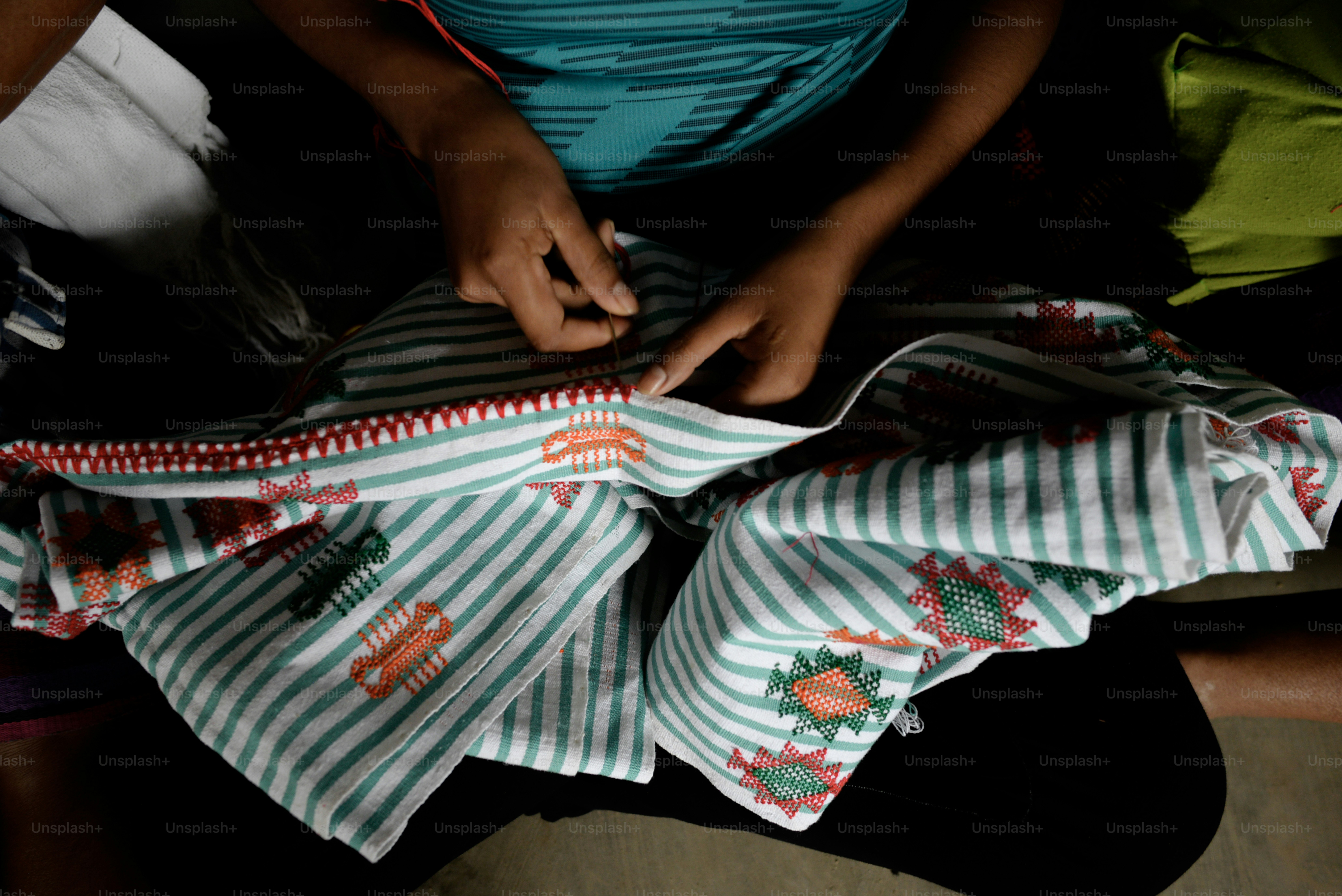 人は装飾的なトリムで生地を縫っています。