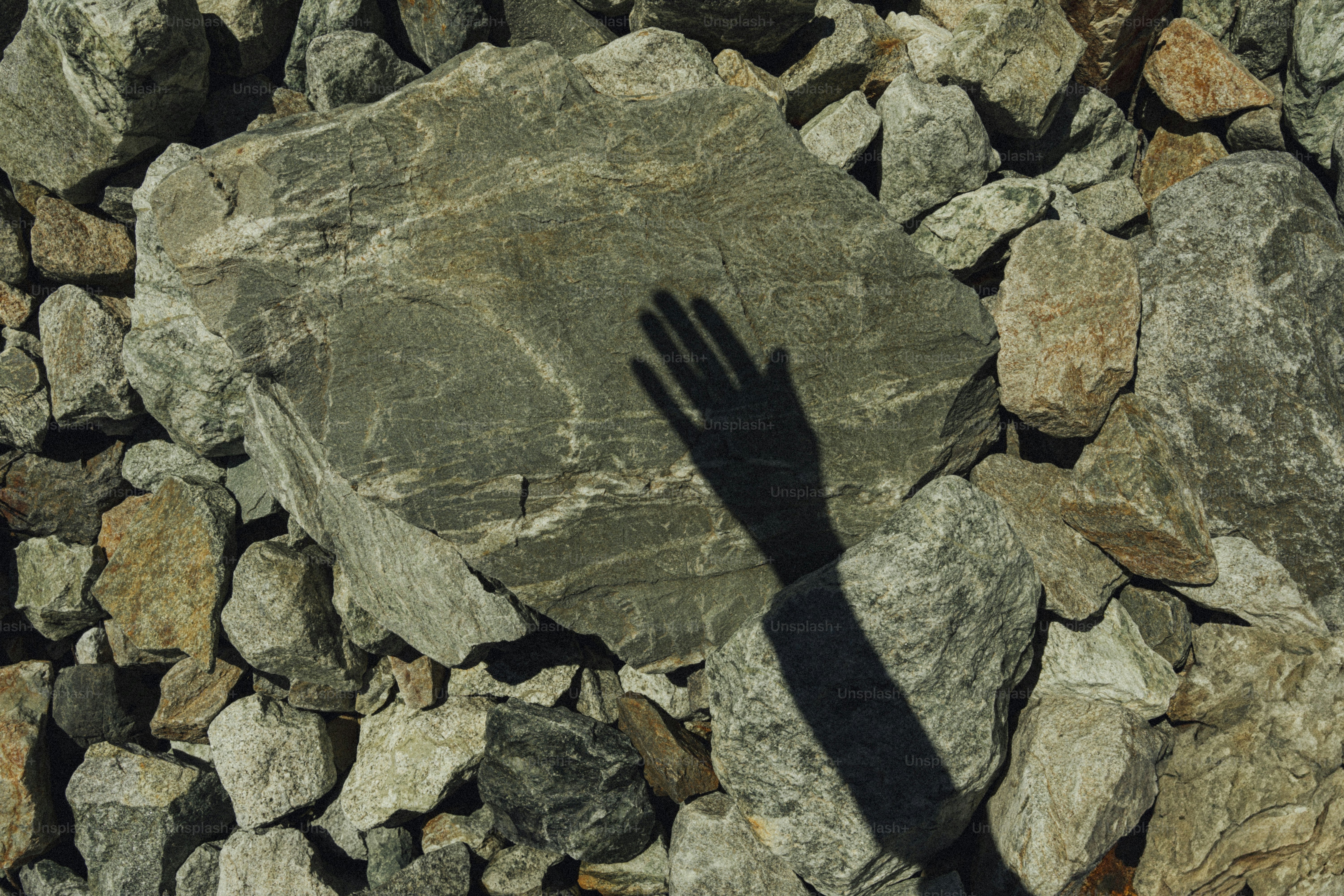Shadow of a hand on a large stone. photo – Shadow Image on Unsplash