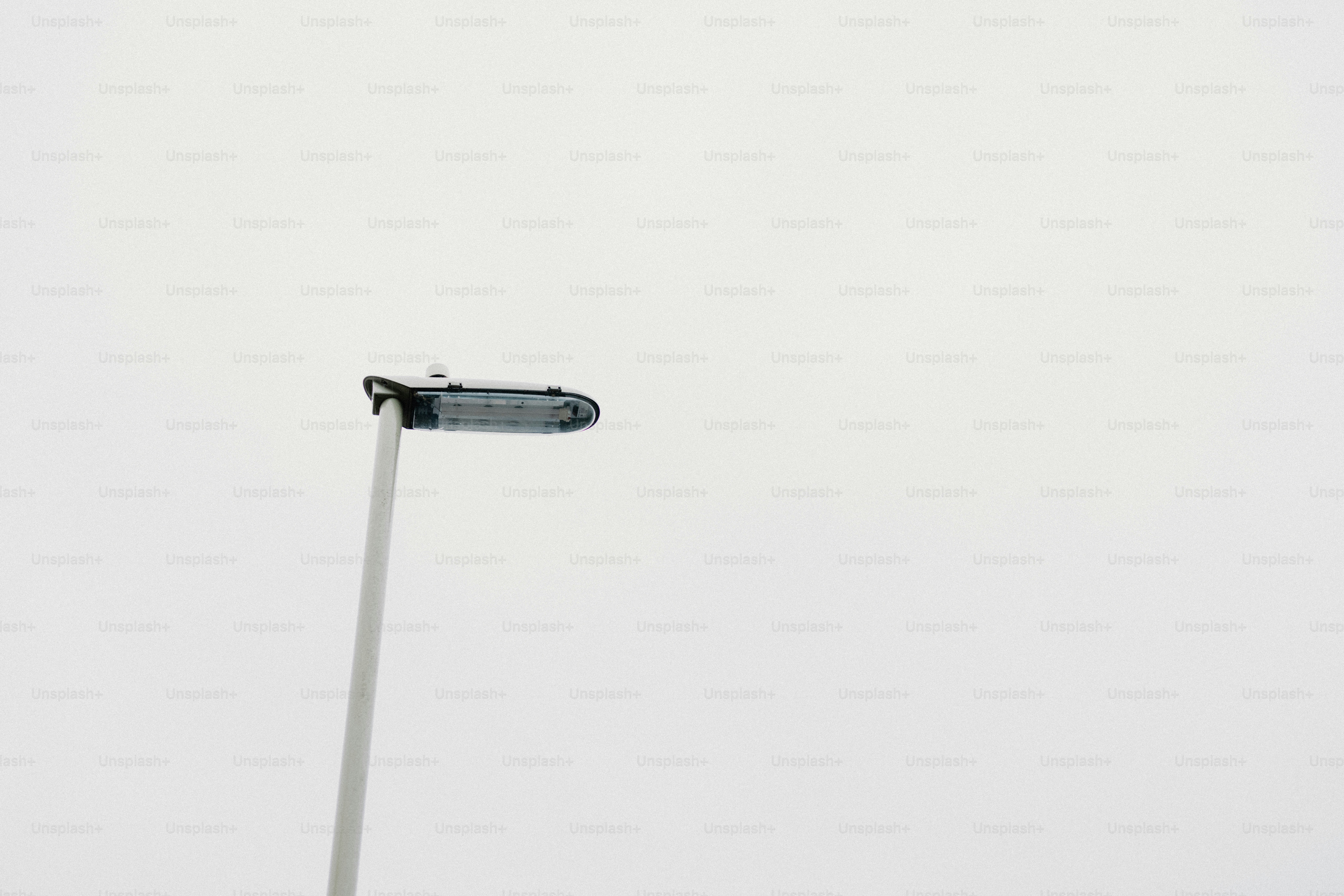 A street lamp stands silhouetted against a white sky.