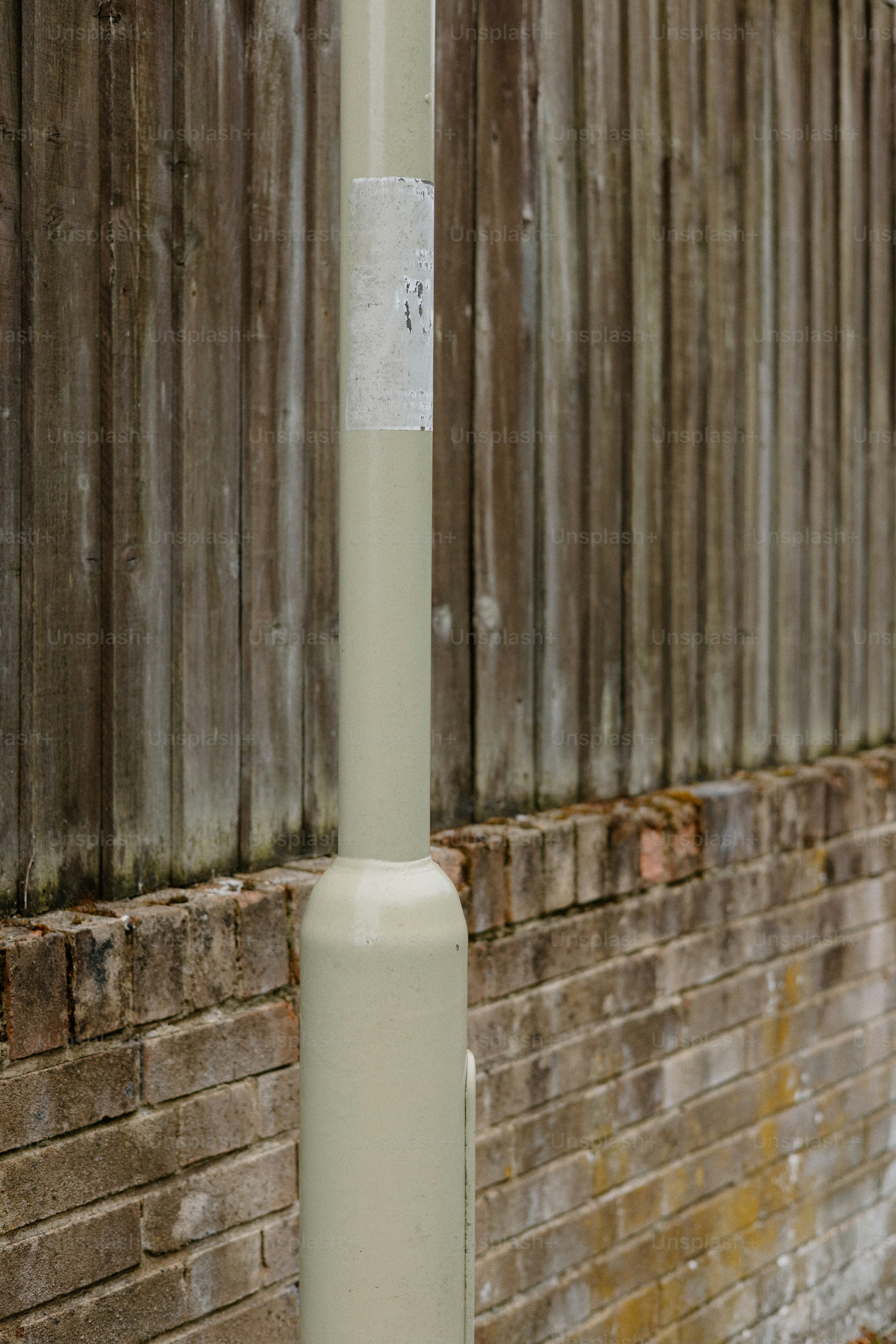 A pole sits in front of a wooden fence.