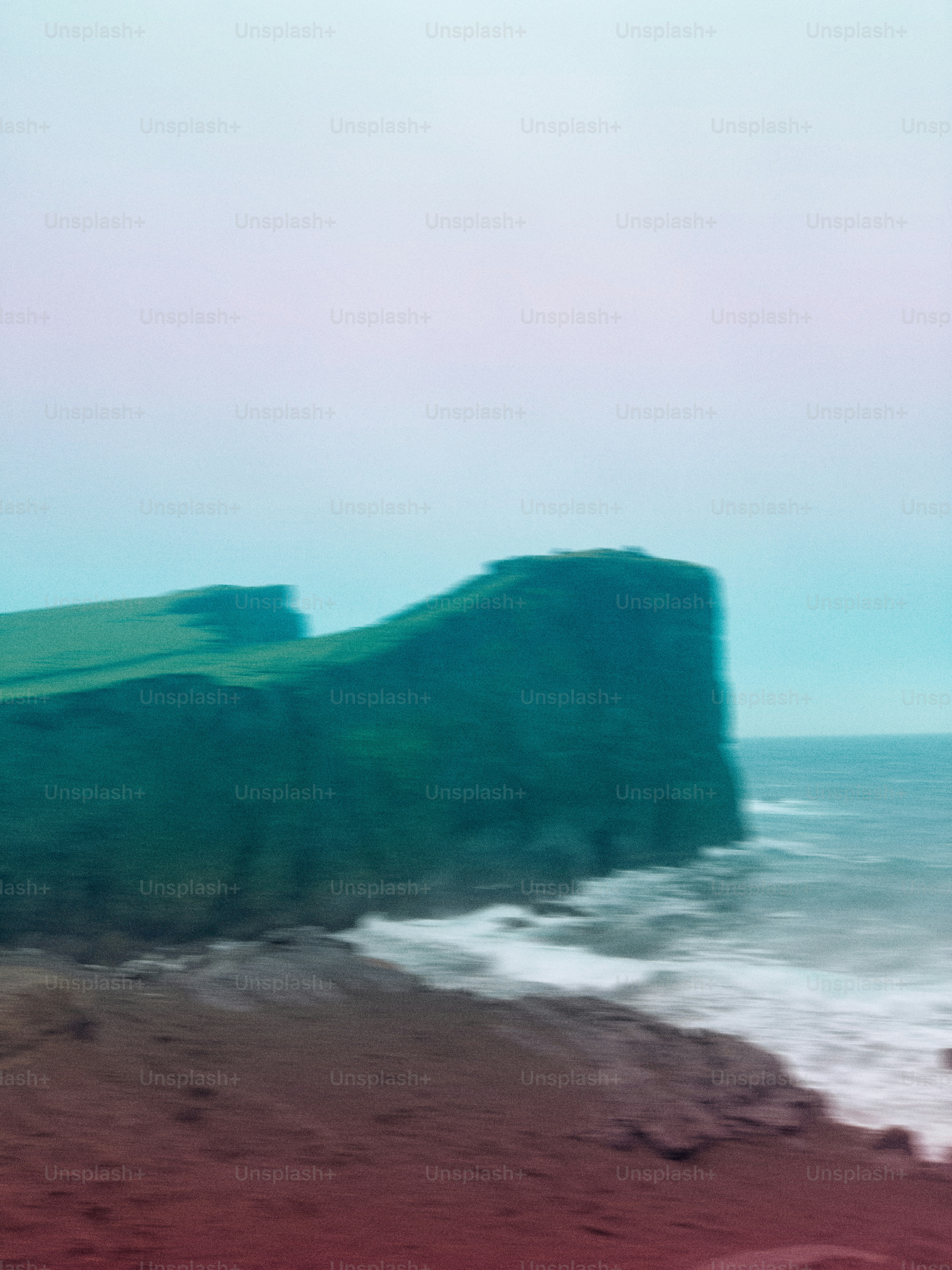 Coastal cliffs meet the ocean under a foggy sky.