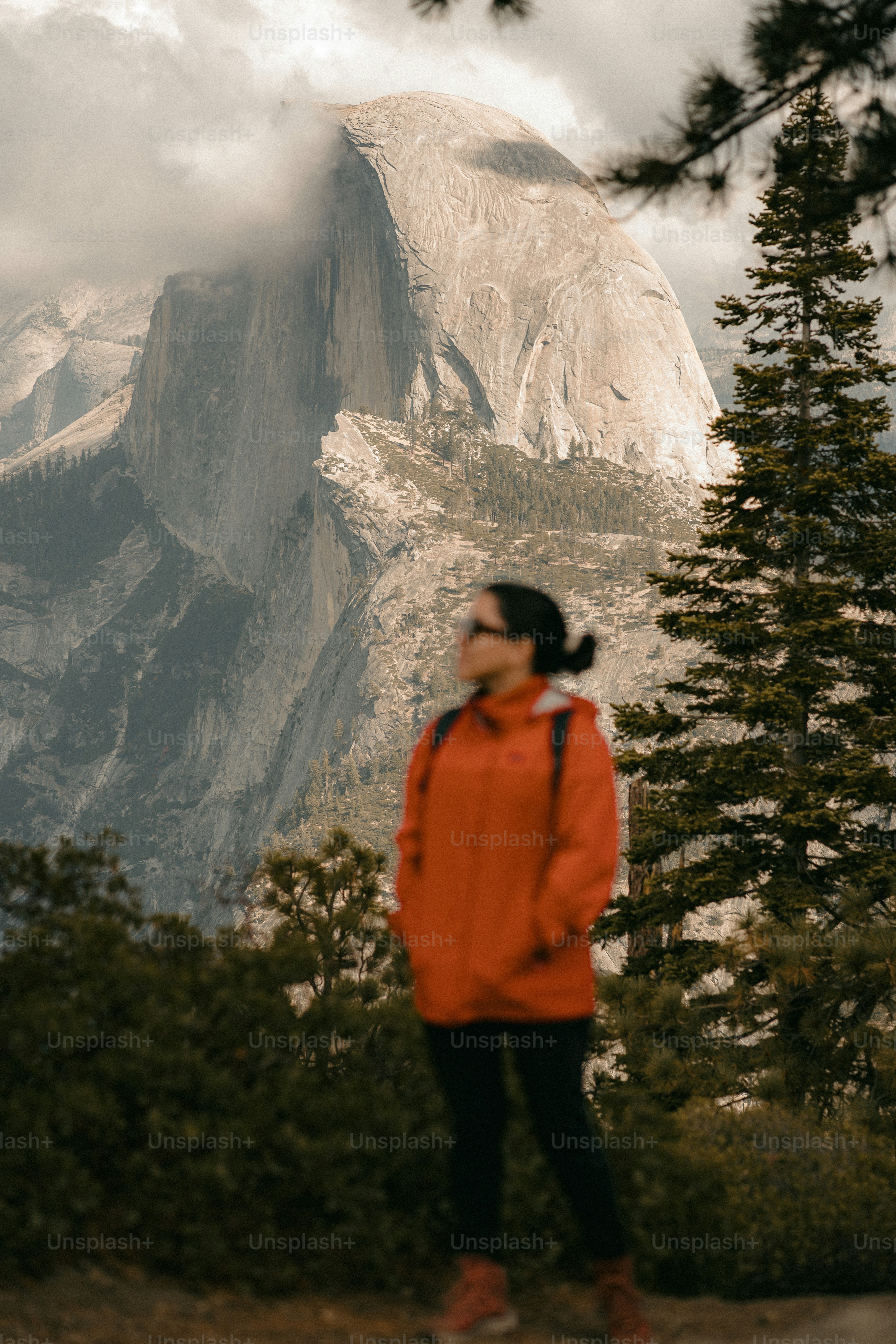 Woman in red jacket looks at mountain.