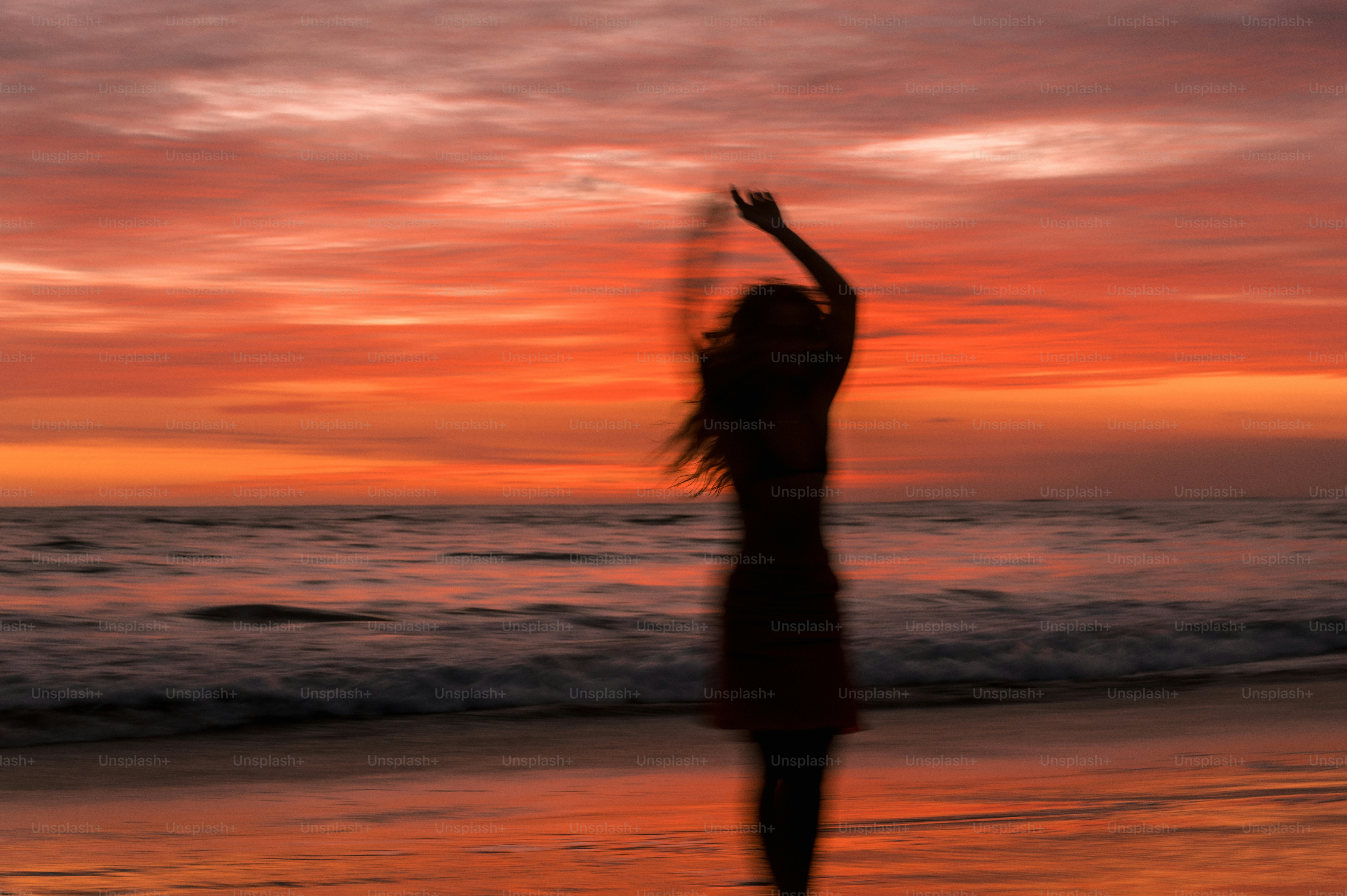 Woman dances on the beach at a beautiful sunset.