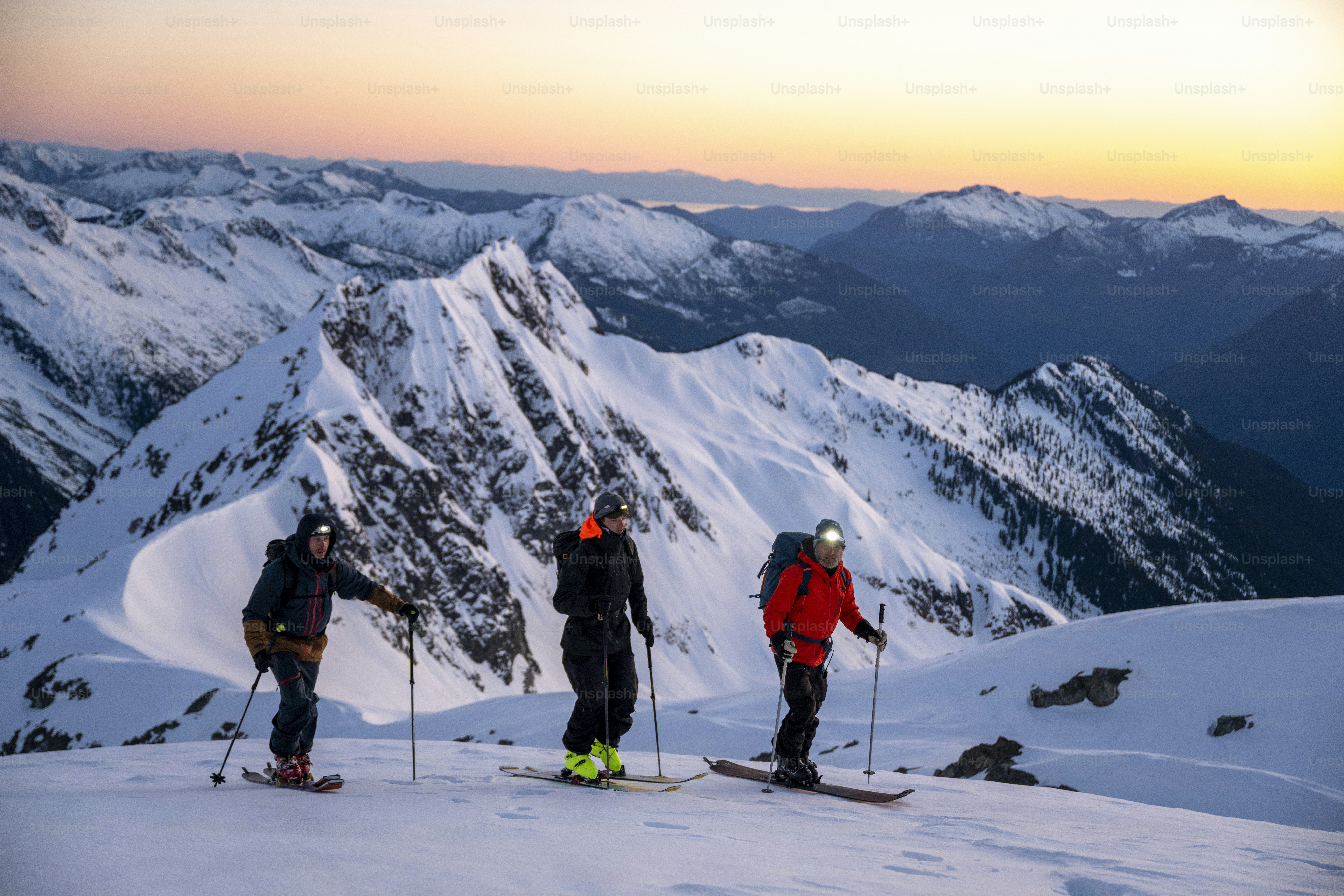 Grupo de esquiadores do backcountry prepara-se para descer a montanha no nascer do sol, escala de Tântalo, B.C