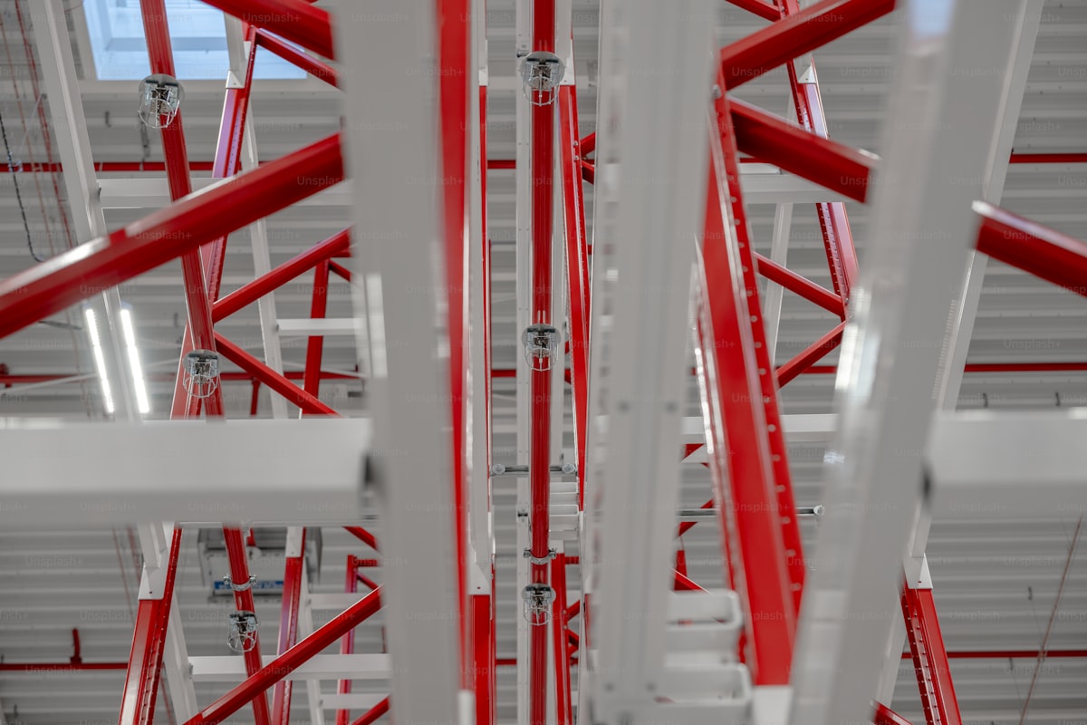 Red fire sprinkler piping through white warehouse racking