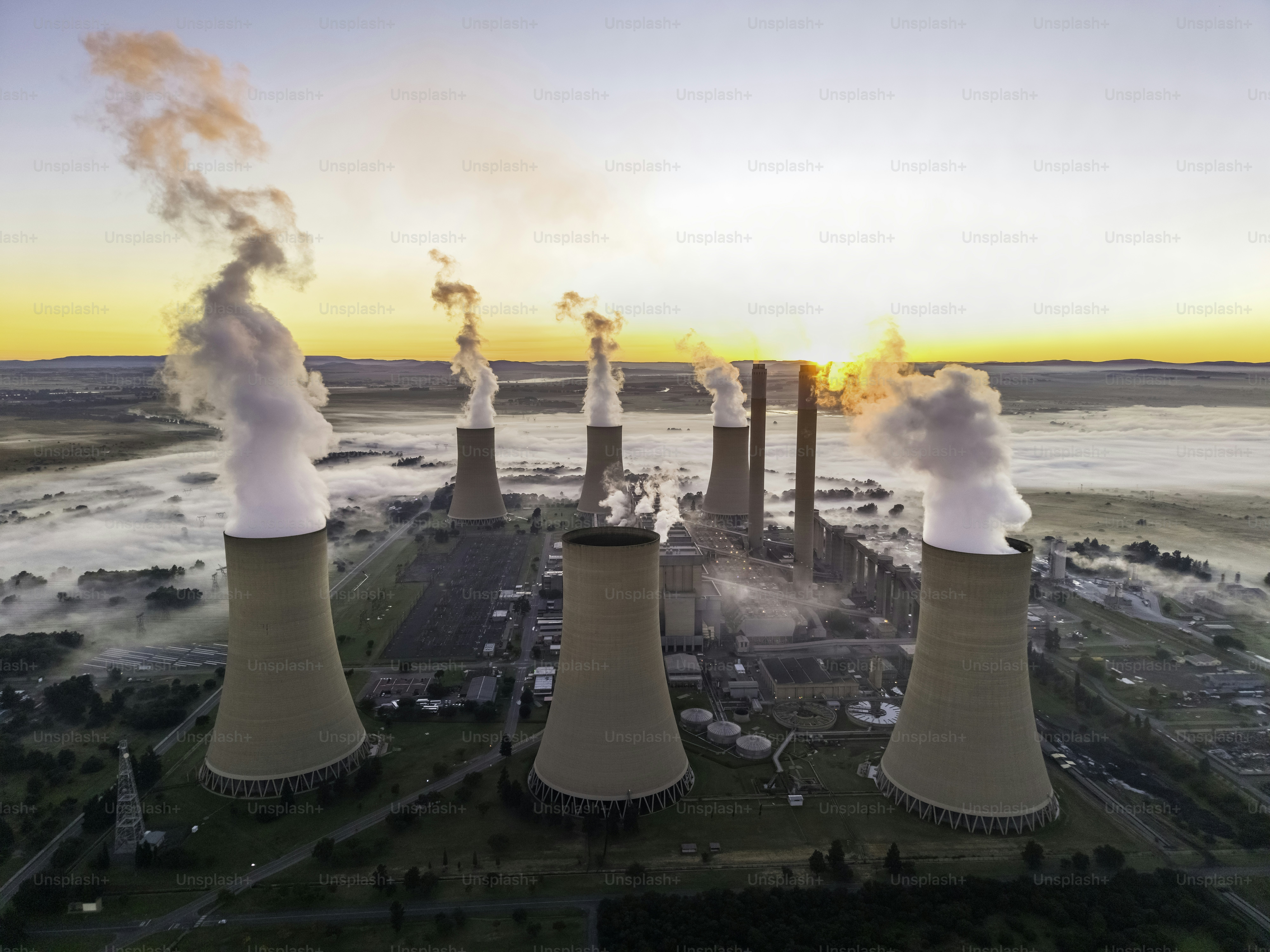 Lethabo Power station seen at  sunrise with the smog and mist over the countryside and steam rising from the cooling towers.