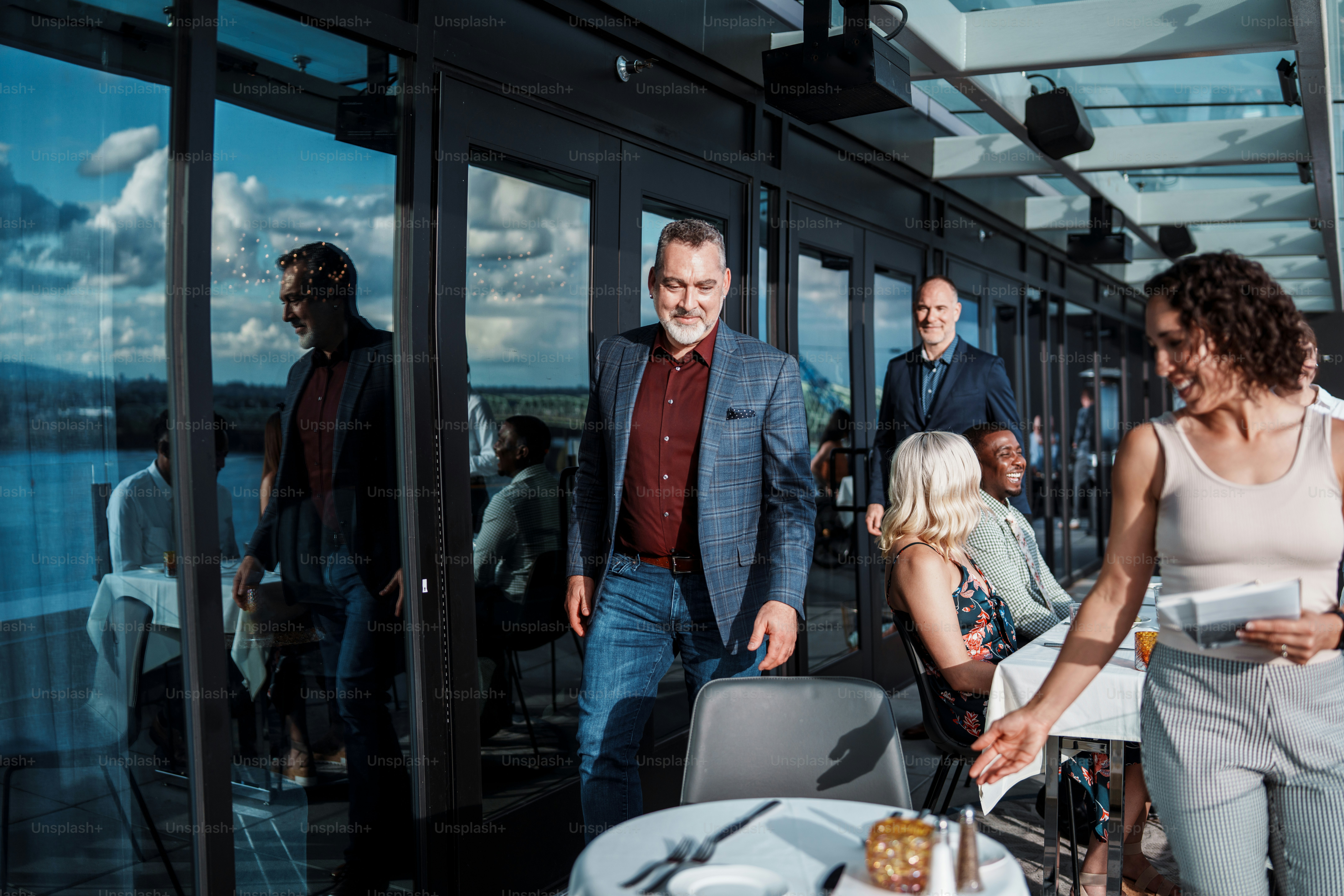 An Eurasian restaurant hostess shows customers, a gay couple, to their table on the rooftop terrace of an upscale restaurant.