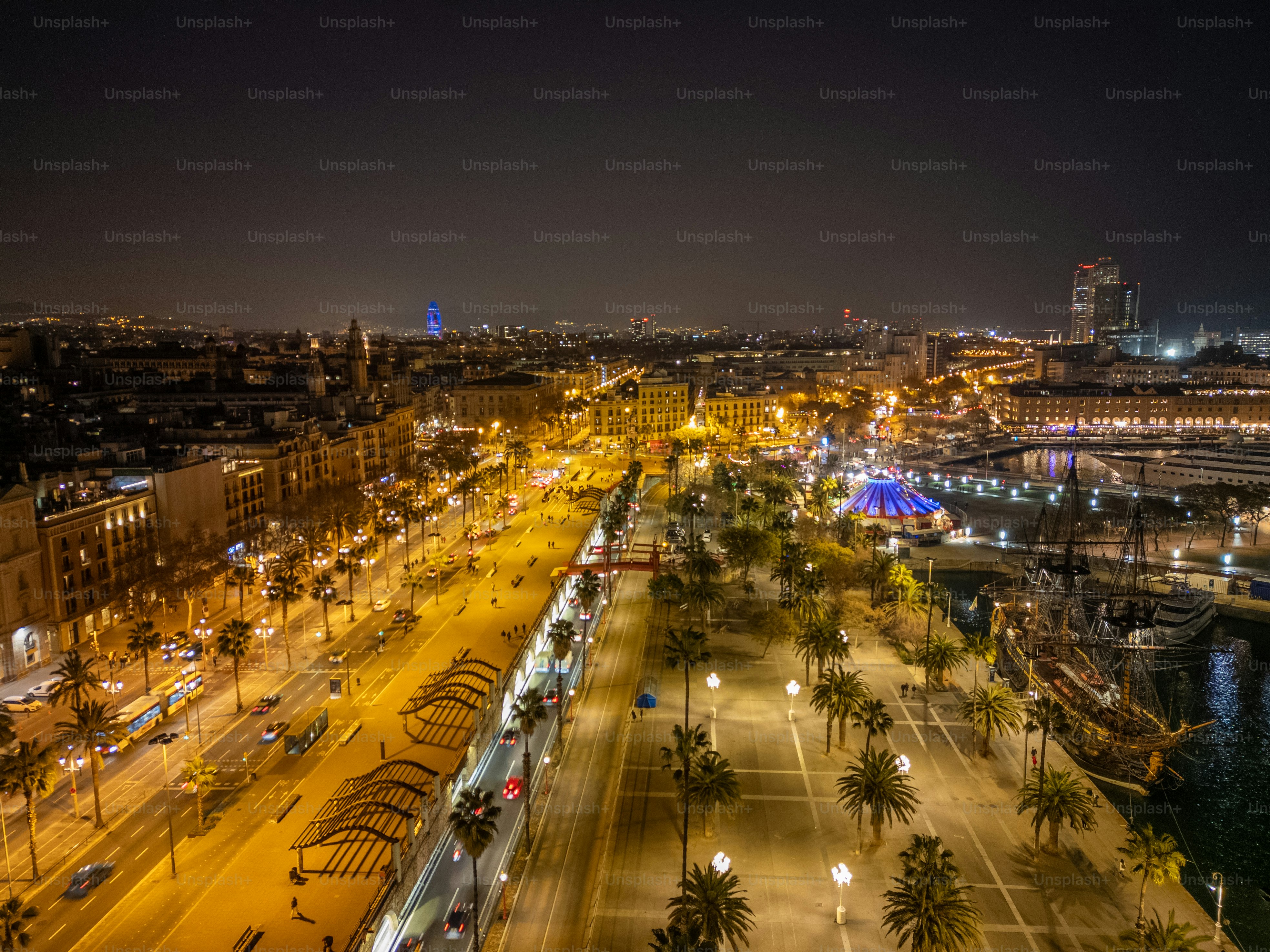 Night view of Barcelona, with radiant street lights lining bustling roads and palm trees, showcasing the city's dynamic urban atmosphere.