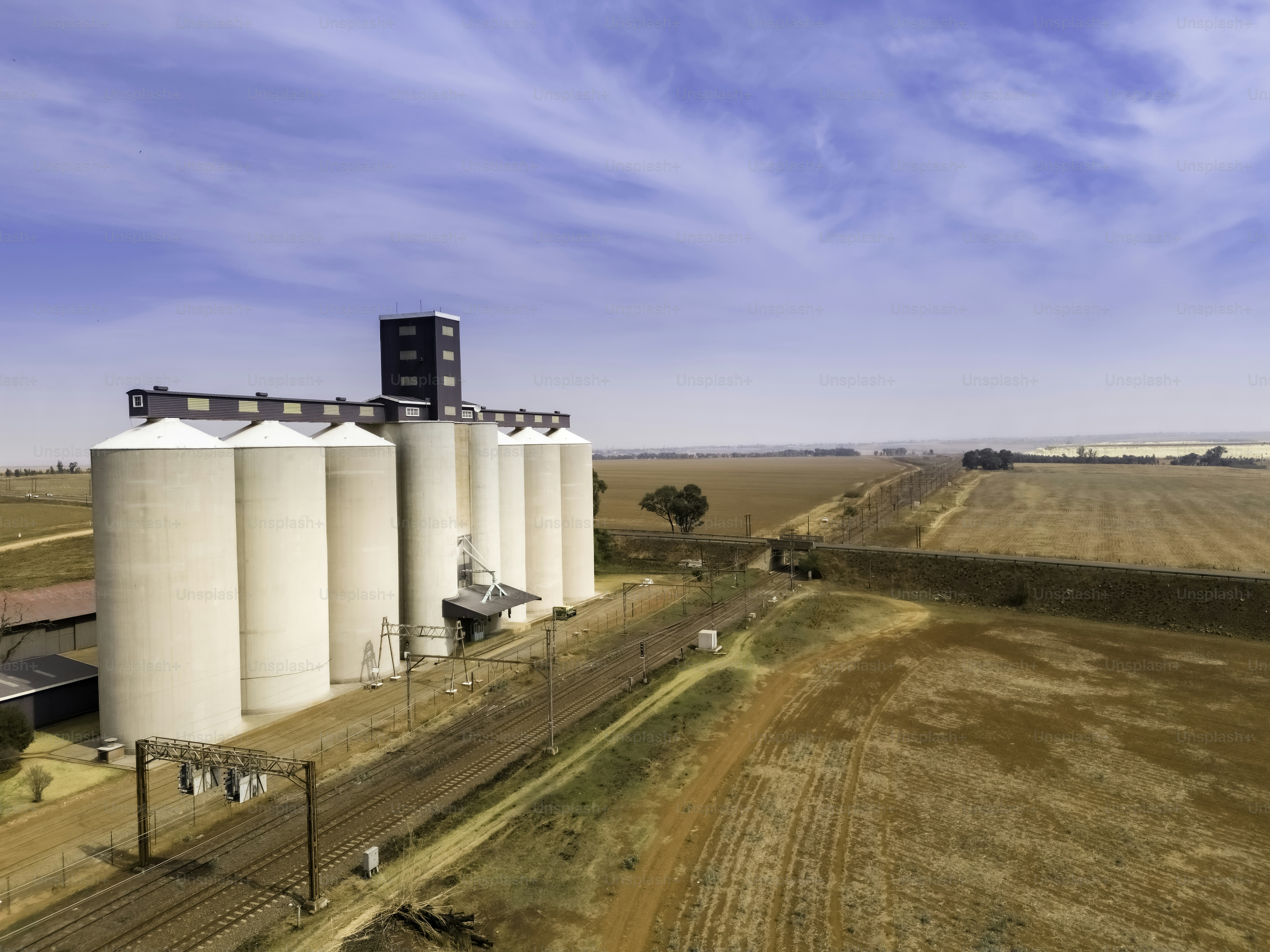 Silos de alimentos en el campo, en los campos agrícolas de Gauteng con una línea de ferrocarril.