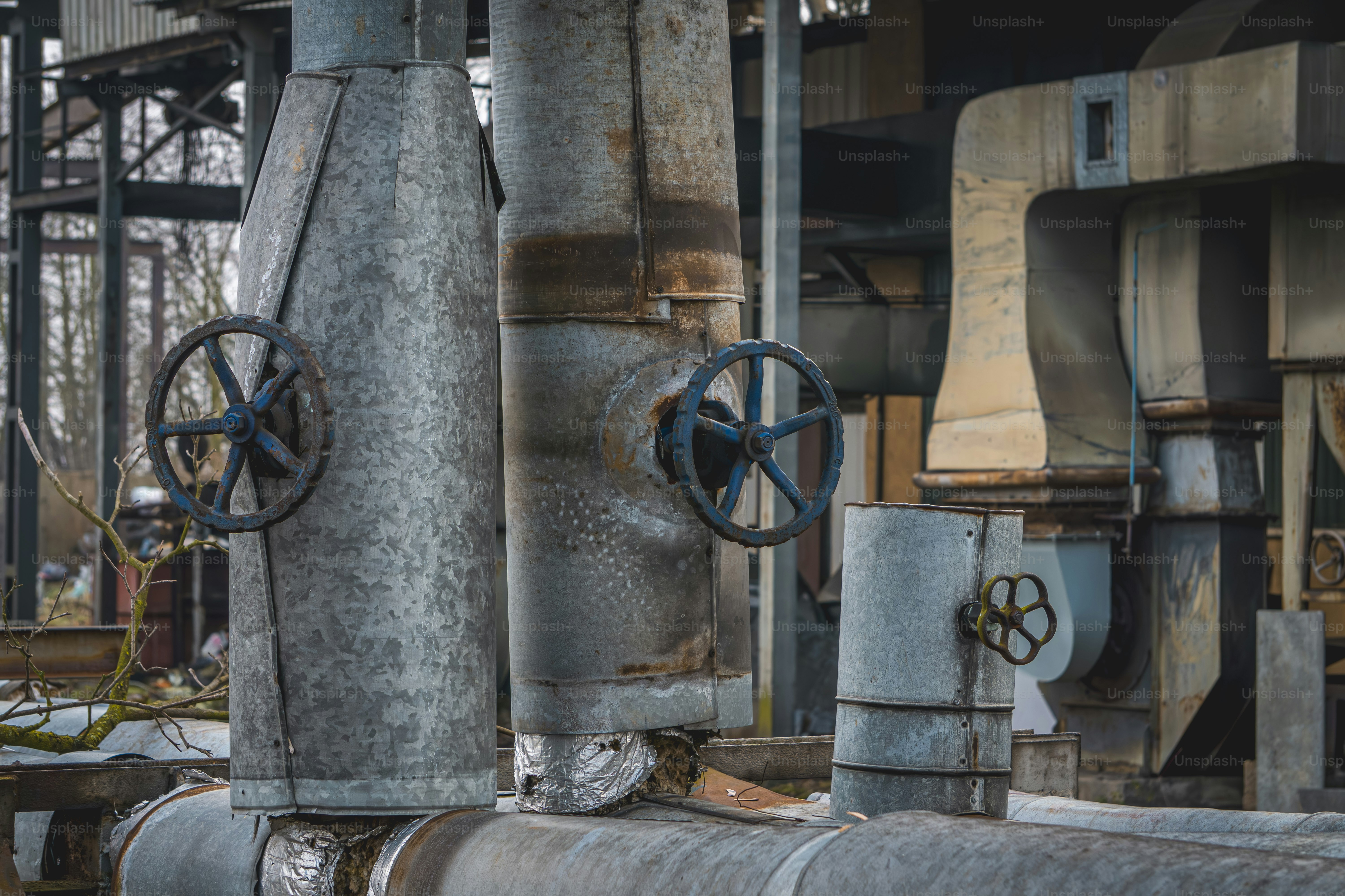 heating network, heat network, pre-insulated pipes, heat supply pipeline covered with bushes going up. old abandoned boiler room of closed production plants. rusty, damaged pipes. valves. industrial atmosphere