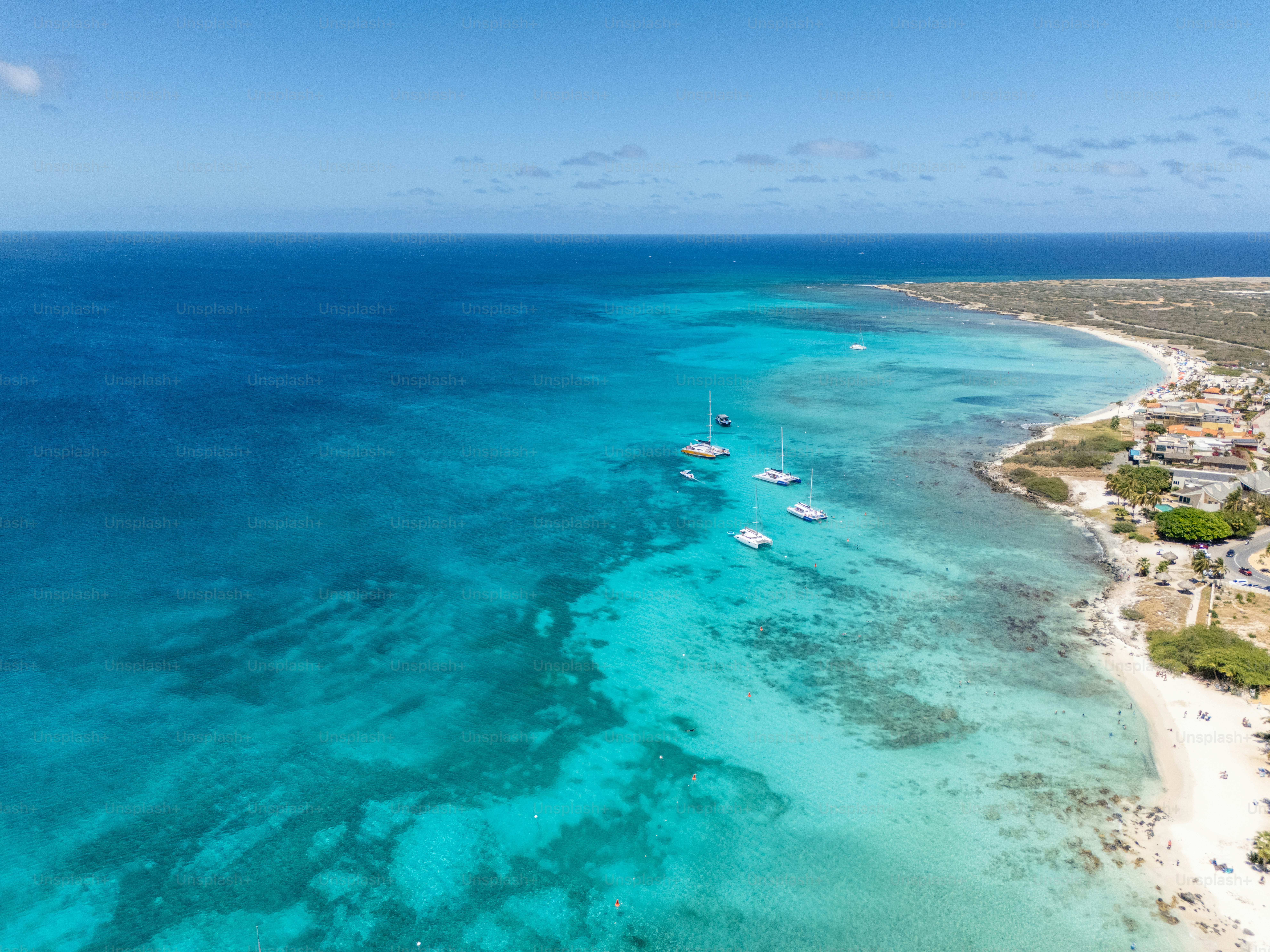 Stunning aerial view of turquoise waters with yachts. Sandy beach with umbrellas. Tropical paradise perfect for vacation and relaxation.