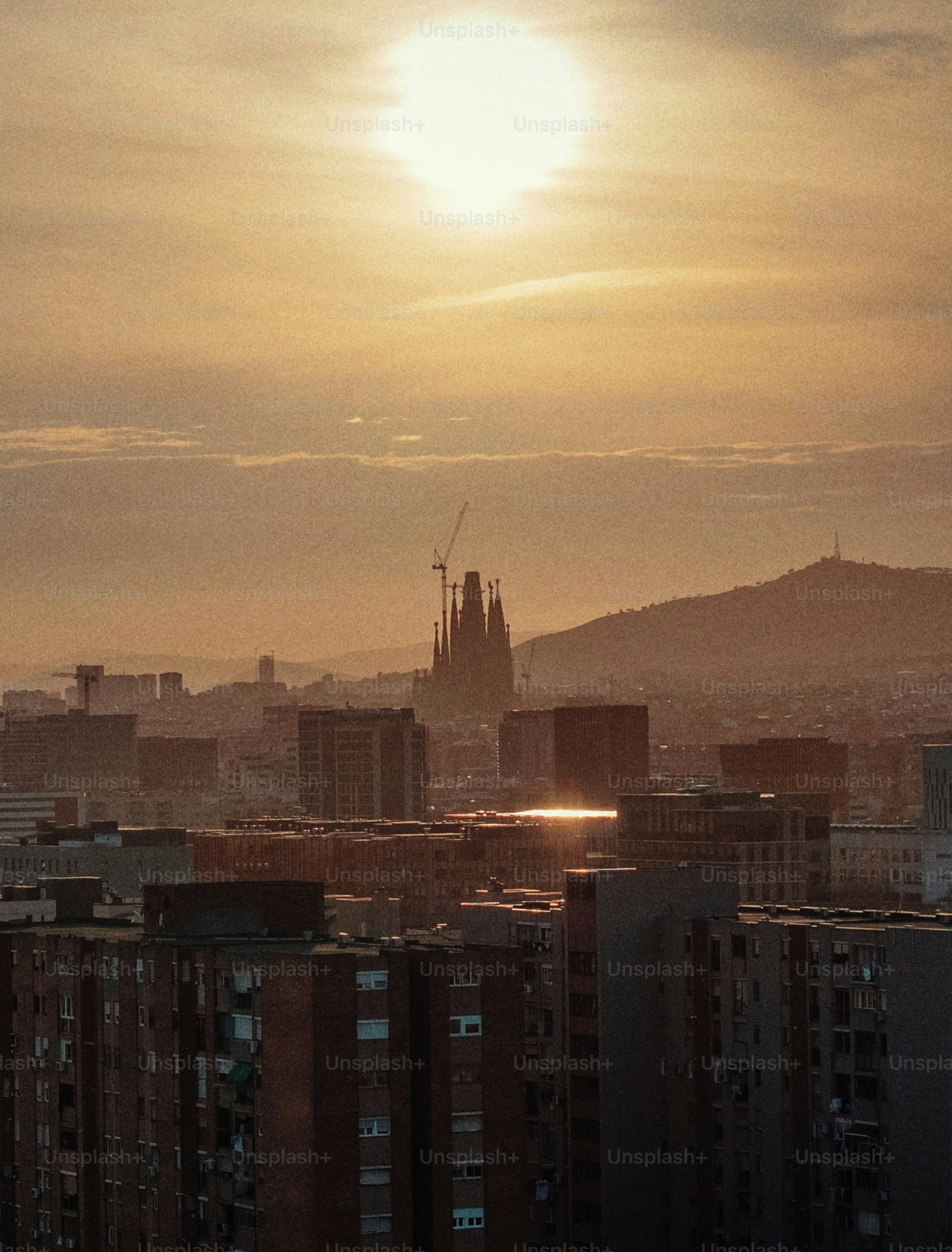 Coucher de soleil derrière l’horizon de Barcelone avec la Torre Agbar et la Sagrada Familia, vue de La Mina avec un grain analogique