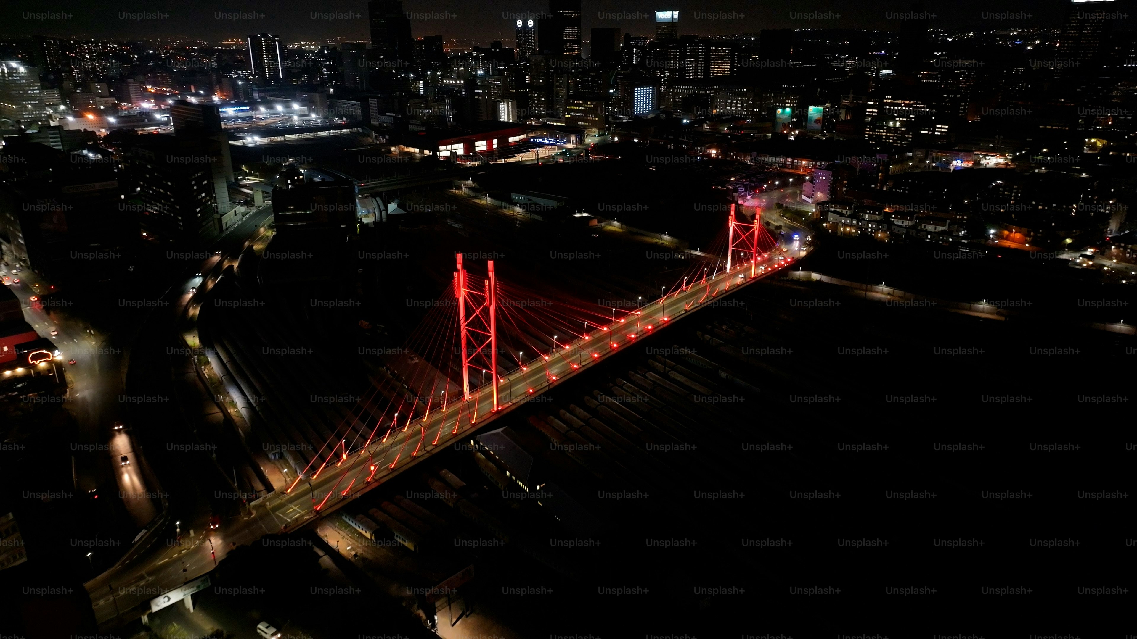 南アフリカのハウテン州ヨハネスブルグにあるマンデラ橋。夜景の町。照光式斜張橋。ヨハネスブルグ、ハウテン州、南アフリカ。ランドマークブリッジ。カラフルなスカイライン。の写真  – Unsplashの都市の画像