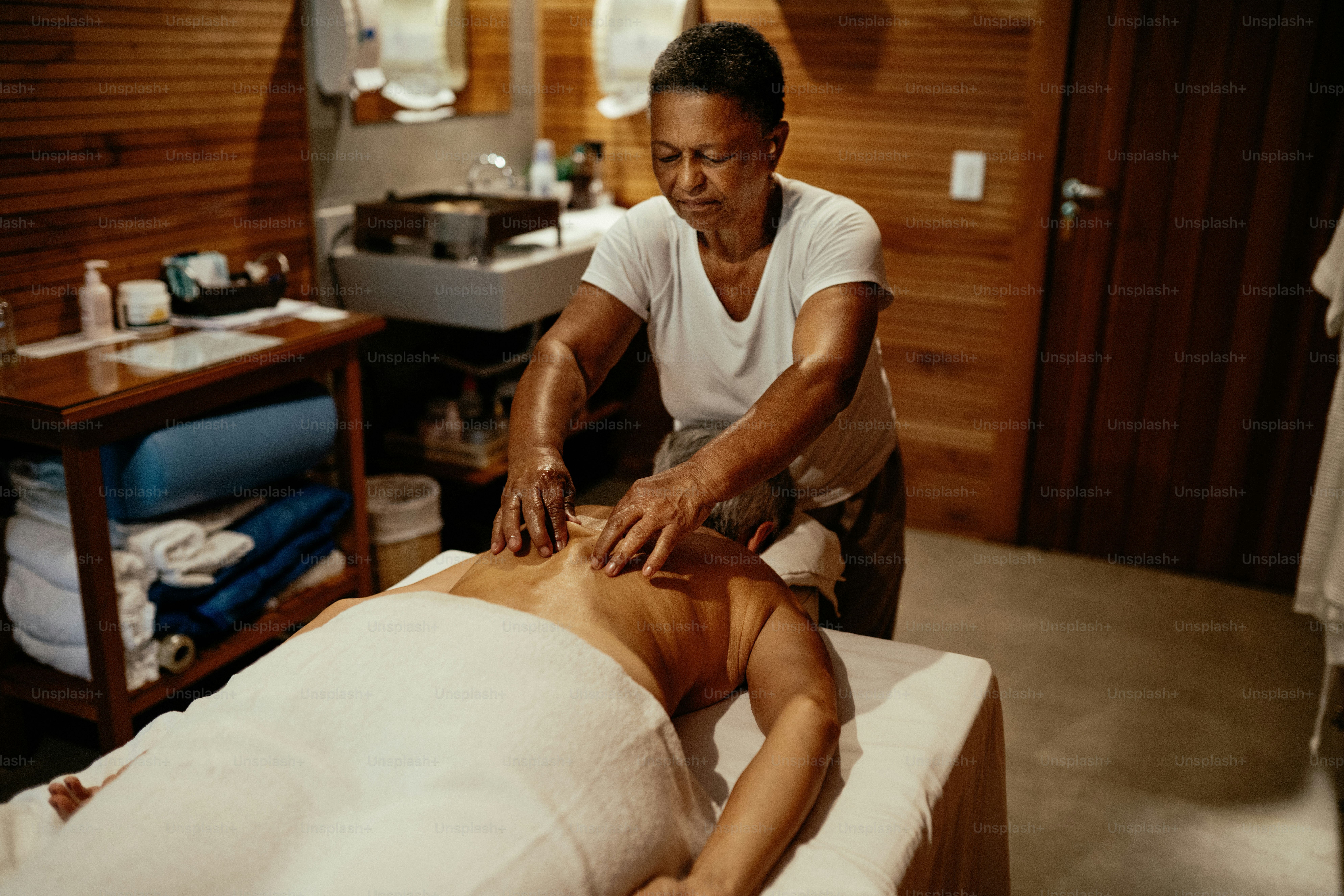 Masseuse giving massage to a mature woman in a luxury spa