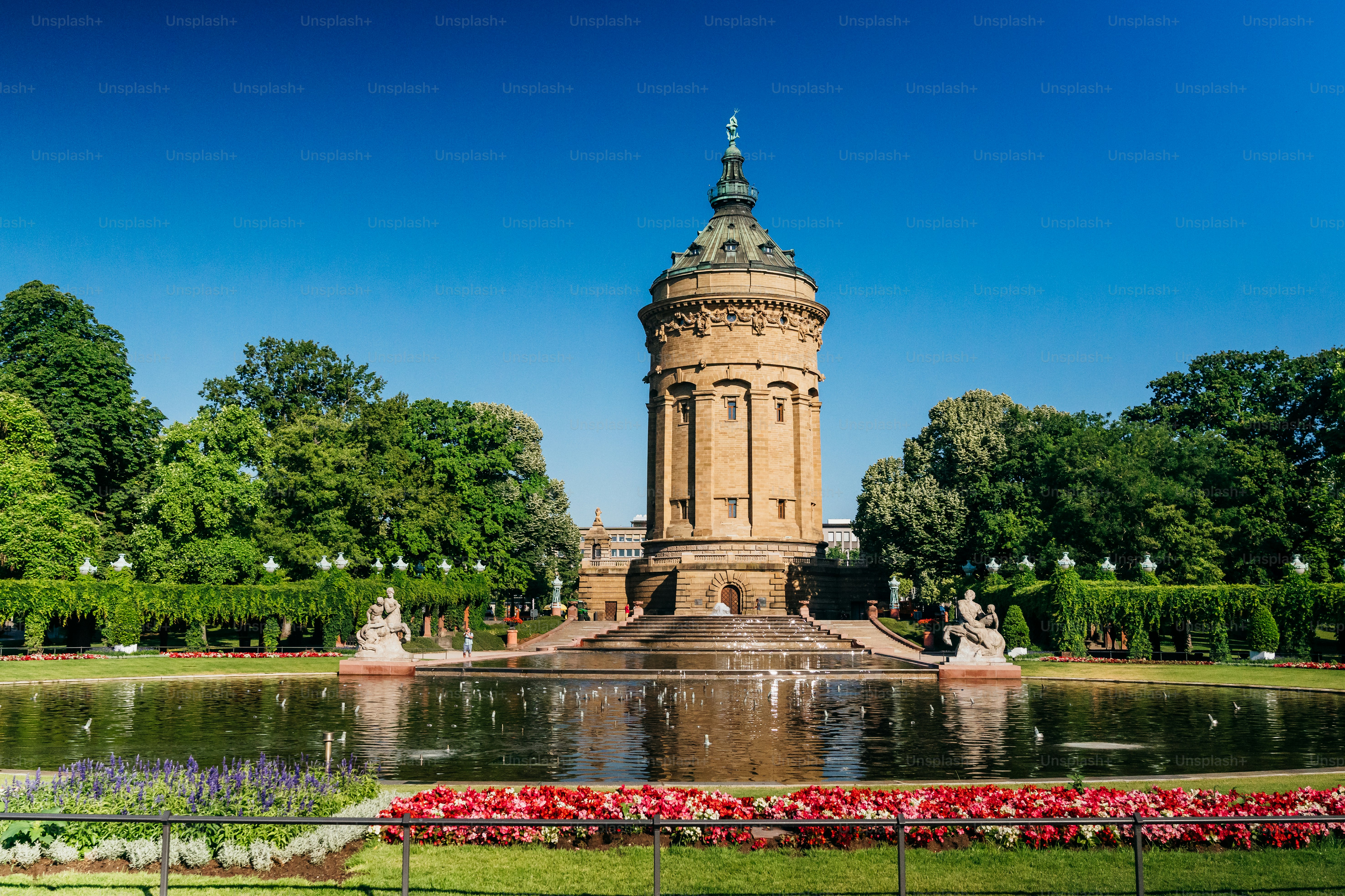 A beautiful day view of the historic water tower in Mannheim, Germany. The  image captures the architecture and surrounding greenery. Friedrichsplatz  with the Mannheim Water Tower (Wasserturm) photo – Architecture Image on, image size:3000x2000
